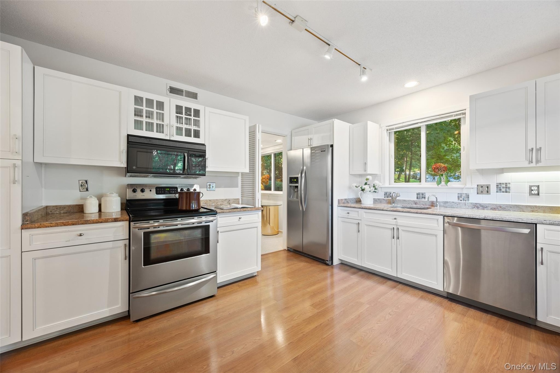 Charming white kitchen with granite countertops, stainless steel appliances, and abundant storage - plenty of room to add a breakfast table for casual