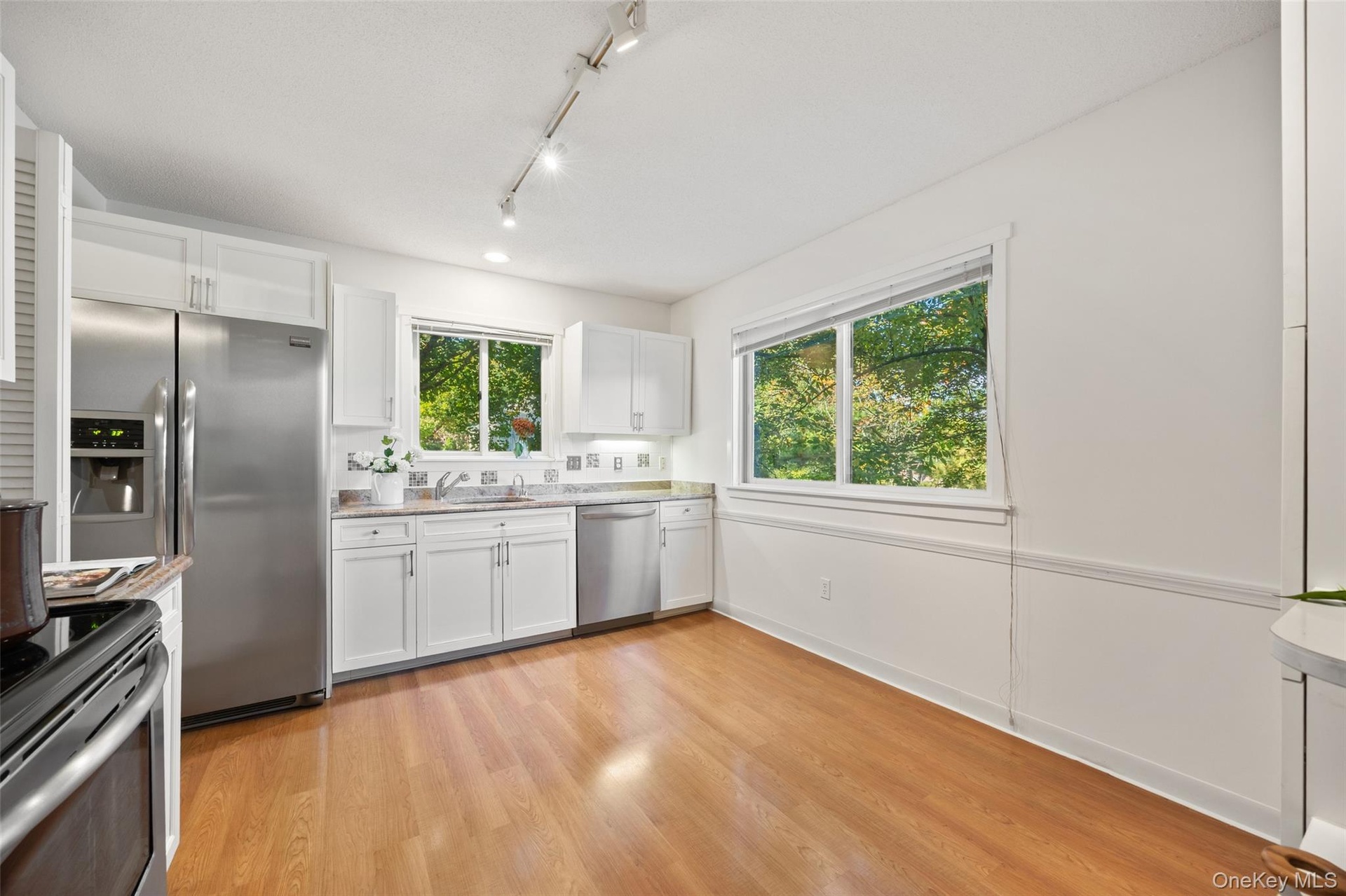 Charming white kitchen with granite countertops, stainless steel appliances, and abundant storage - plenty of room to add a breakfast table for casual