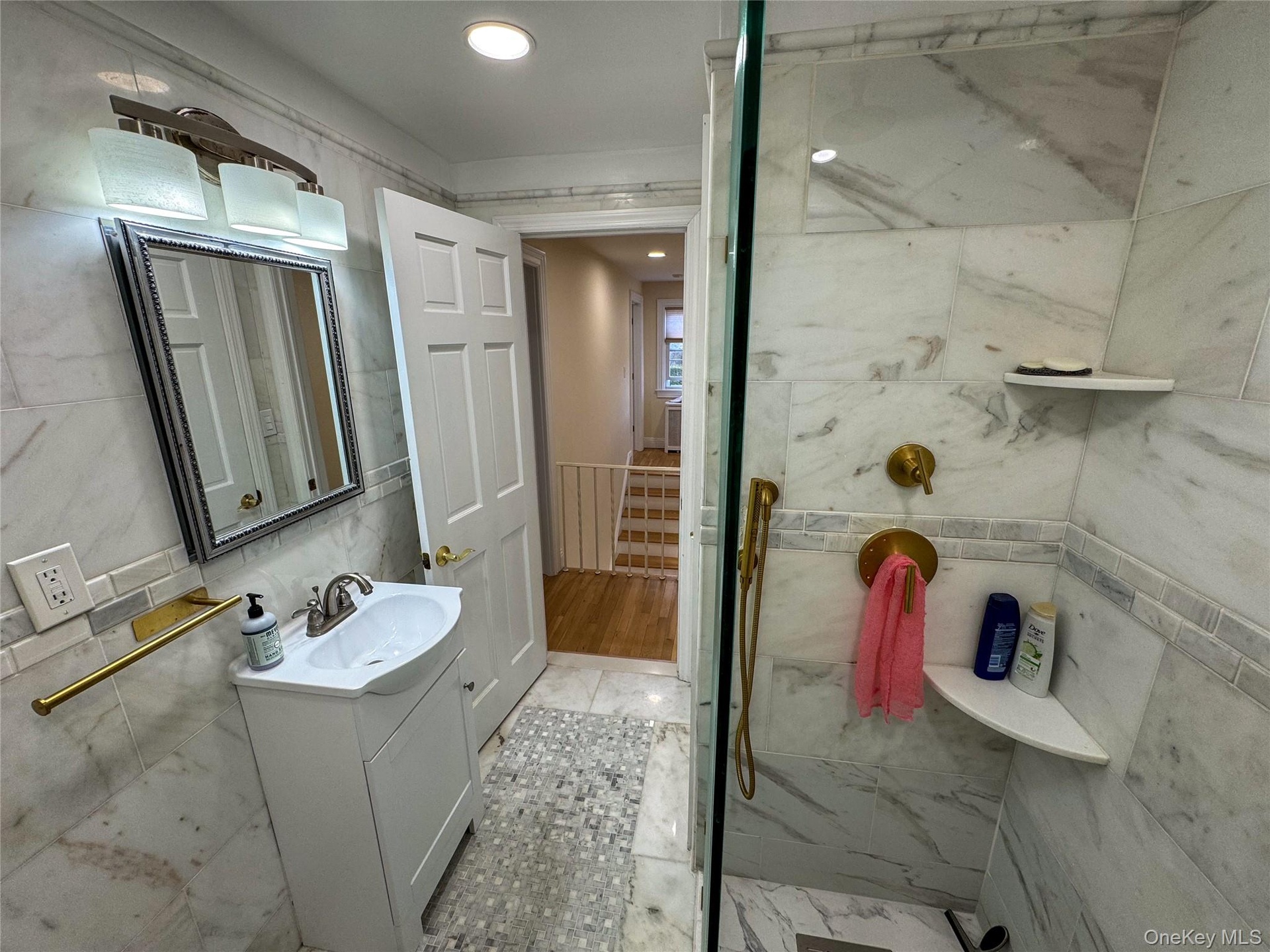 Shower with full-height tile surround, brass fixtures, and built-in shelving