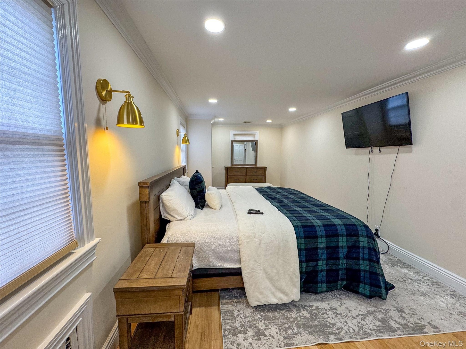 Wood-finish flooring with a decorative area rug, recessed ceiling lighting, and crown molding