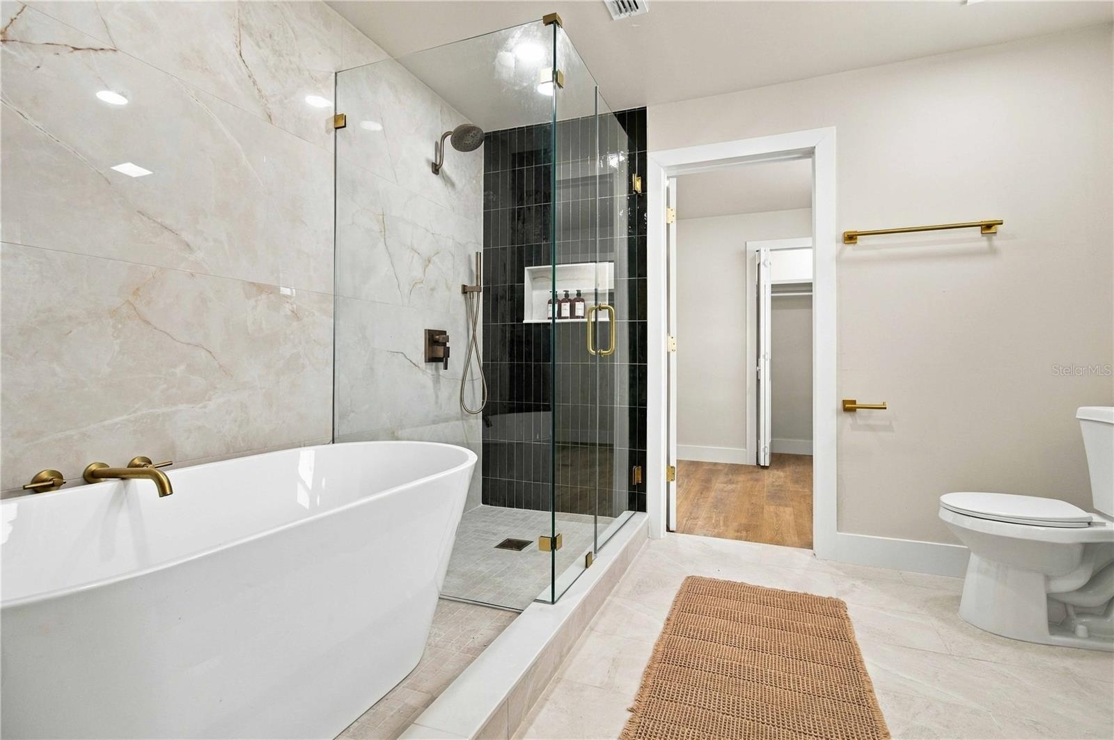 Primary bath with soaking tub, a walk in shower, and leading into walk in closet