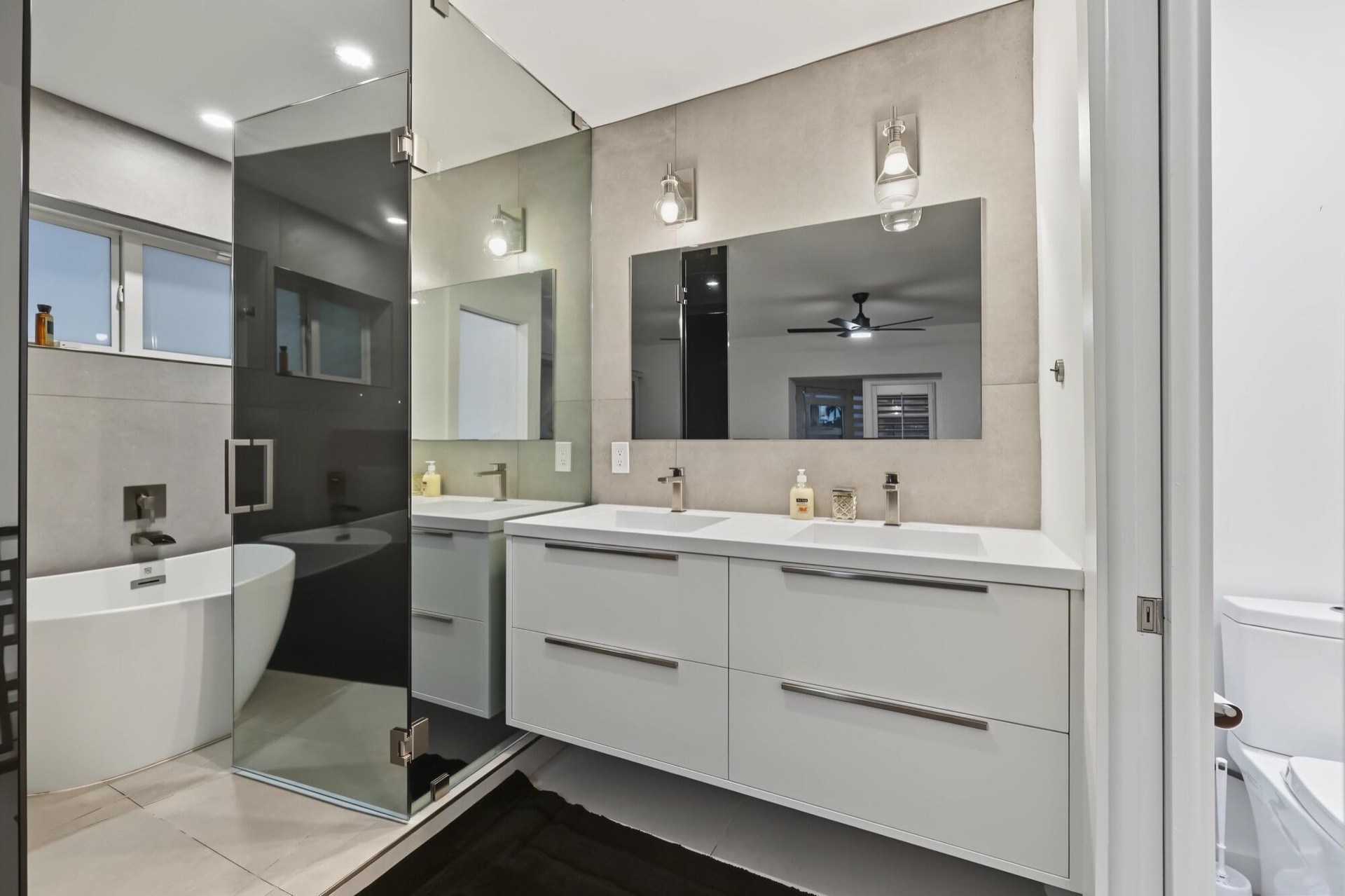 Modern bathroom featuring a floating dual vanity with integrated sinks, a freestanding tub, and a glass-enclosed shower