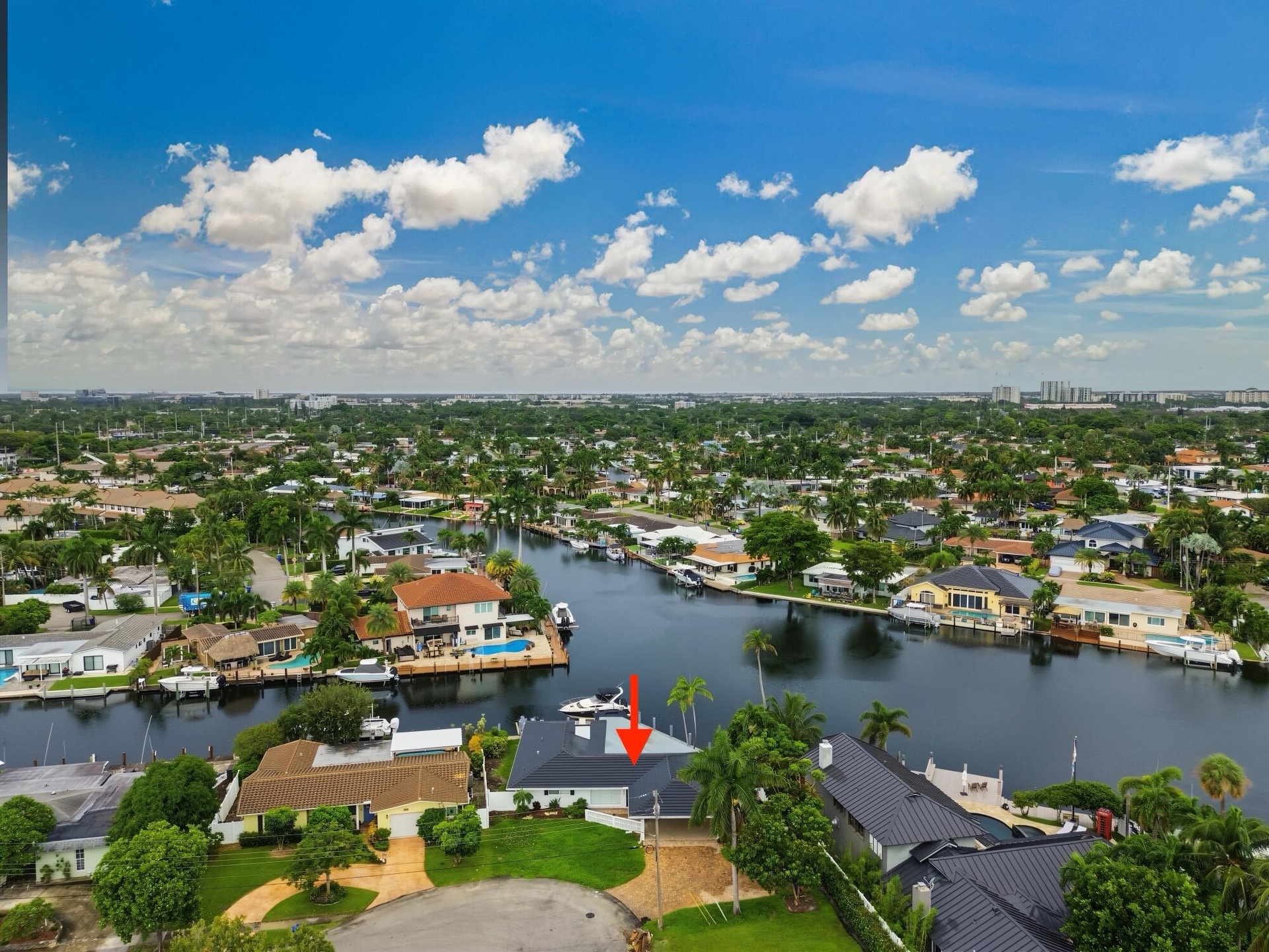 Waterfront property featuring a private boat dock, lush green landscaping, and a circular driveway