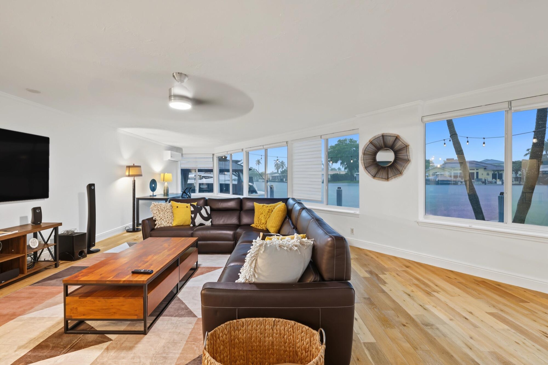 Light wood-finish flooring, recessed ceiling lighting, a ceiling fan, multiple windows with white trim, and white walls