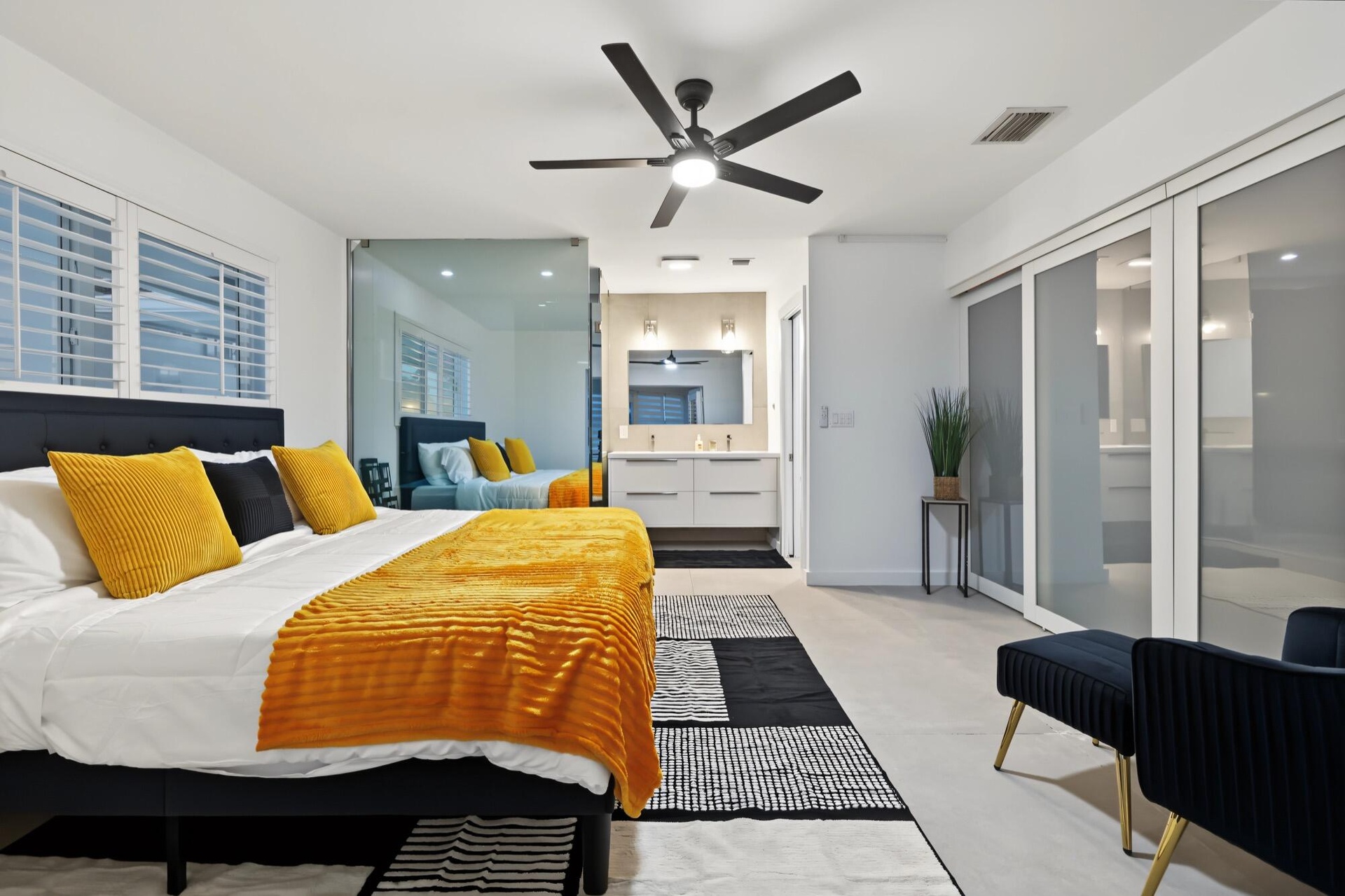 Room featuring a ceiling fan, white plantation shutters, glass partition, sliding opaque closet doors, and wood-finish flooring