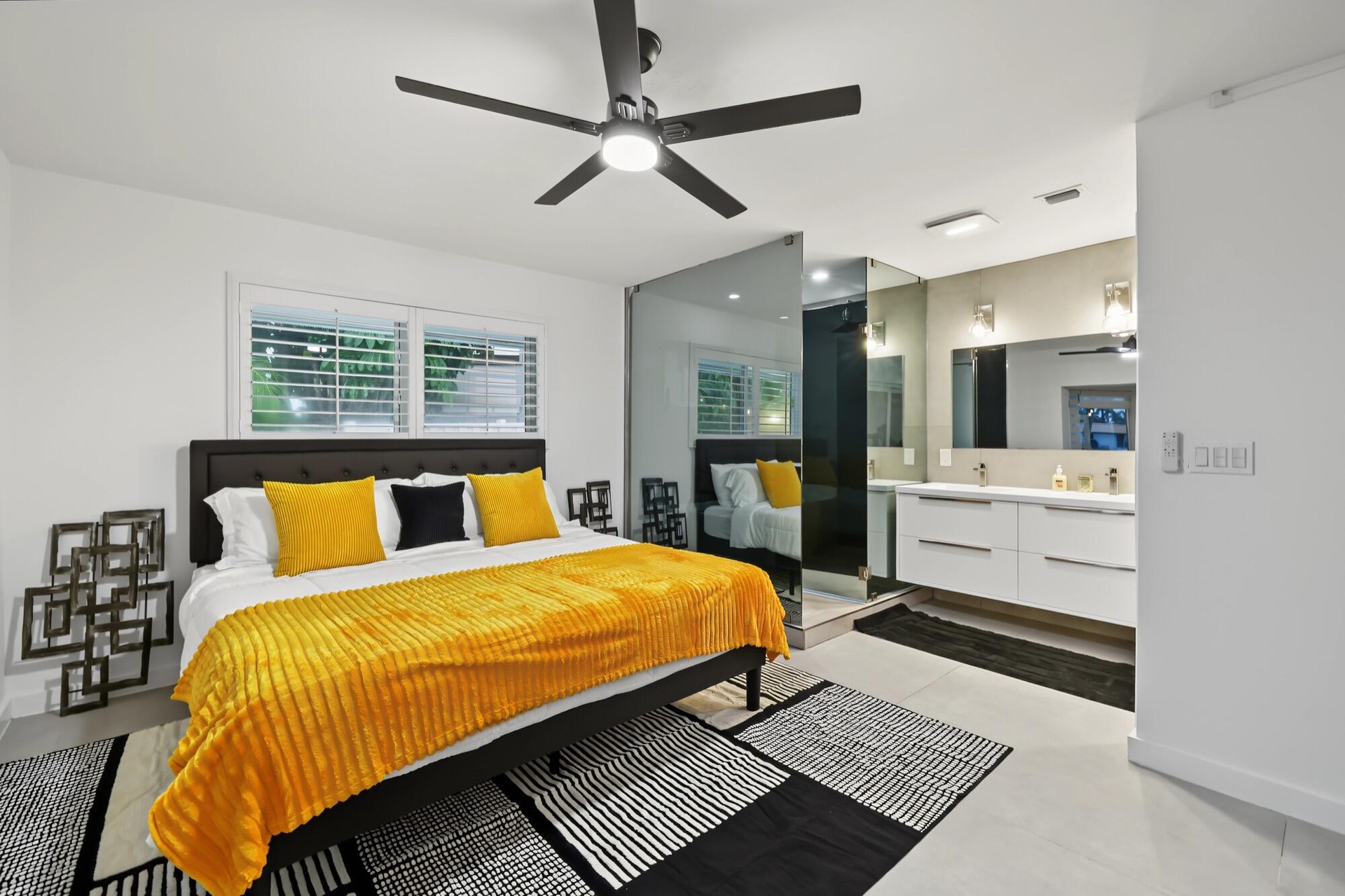 Contemporary room featuring a black ceiling fan, dual windows with plantation shutters, a floating double vanity with rectangular sinks, and a mirrore
