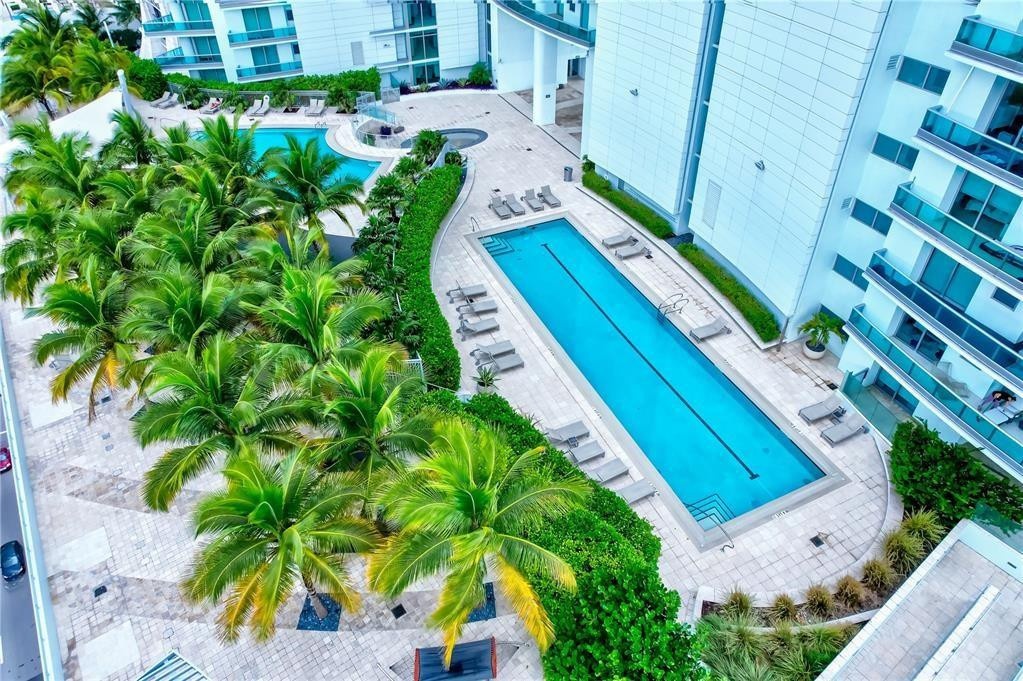 Expansive outdoor amenities featuring a lap pool with lane markers, an additional freeform pool, and a circular spa