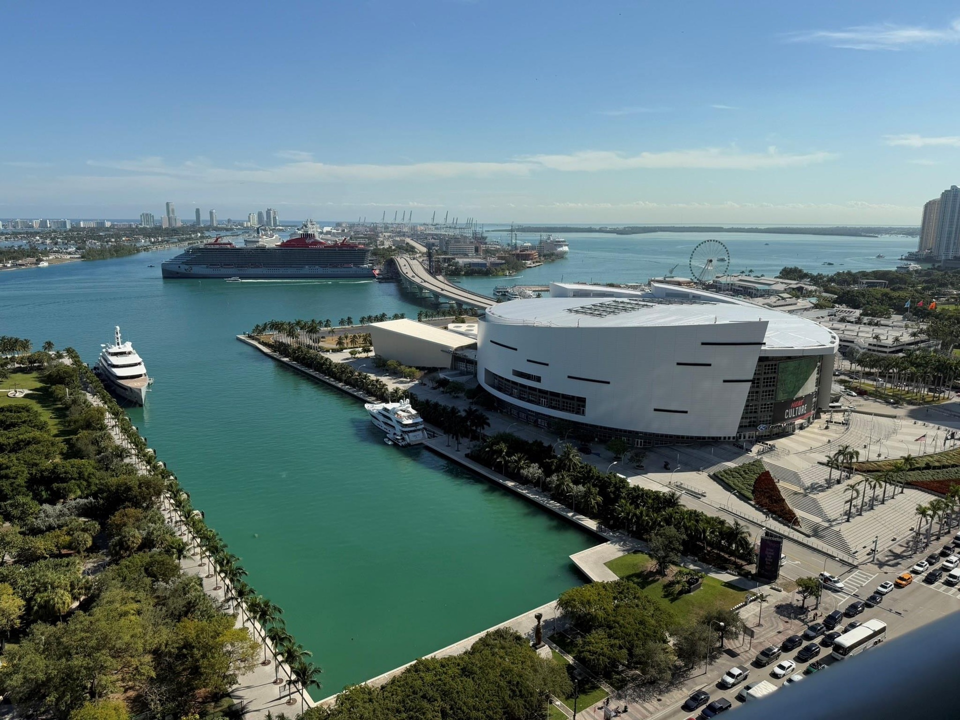 Expansive water frontage with marina access, featuring a large cruise ship, surrounding cityscape, and a prominent arena structure
