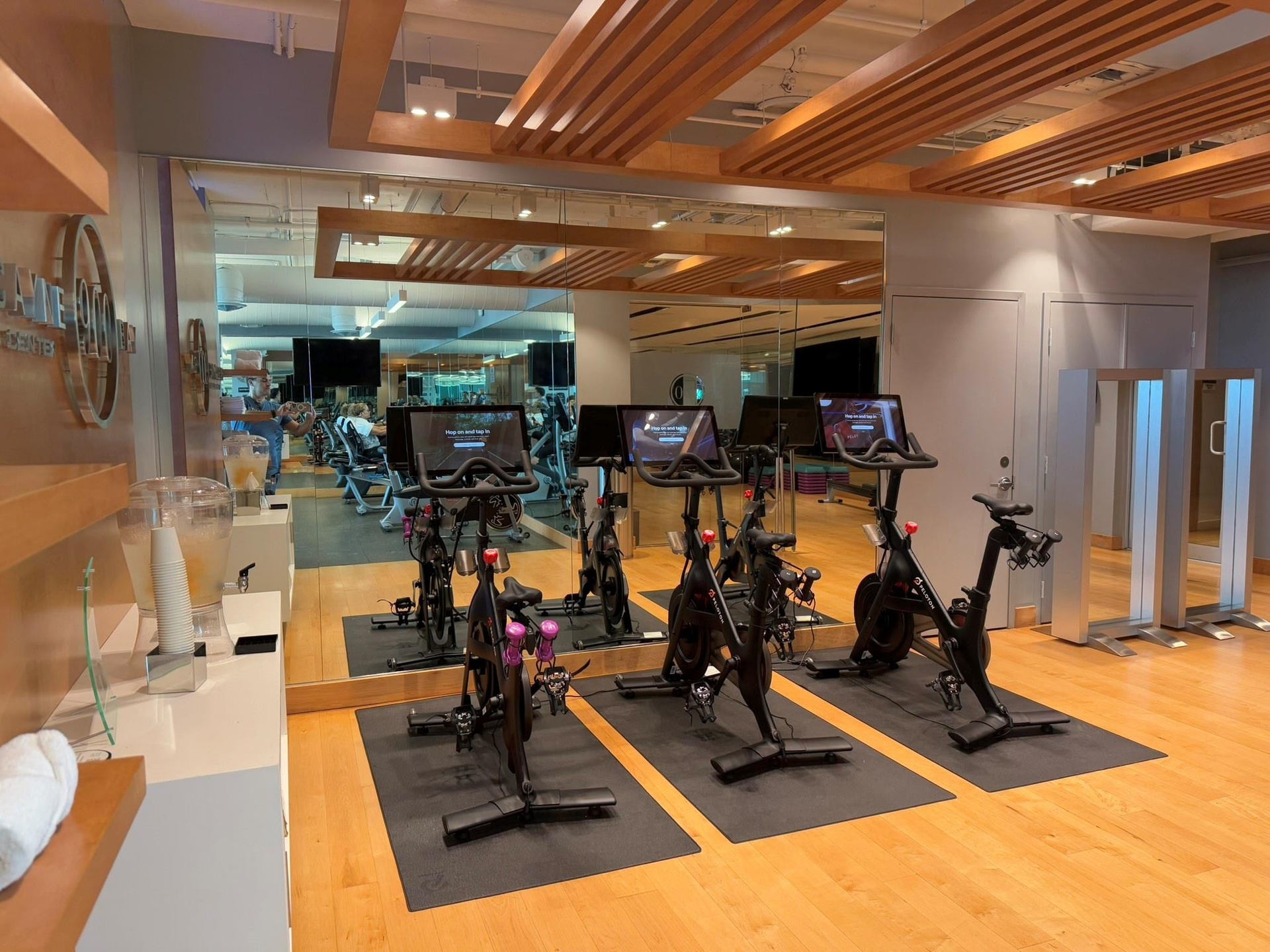Fitness center featuring wood-finish flooring, mirrored walls, and exposed wood ceiling beams
