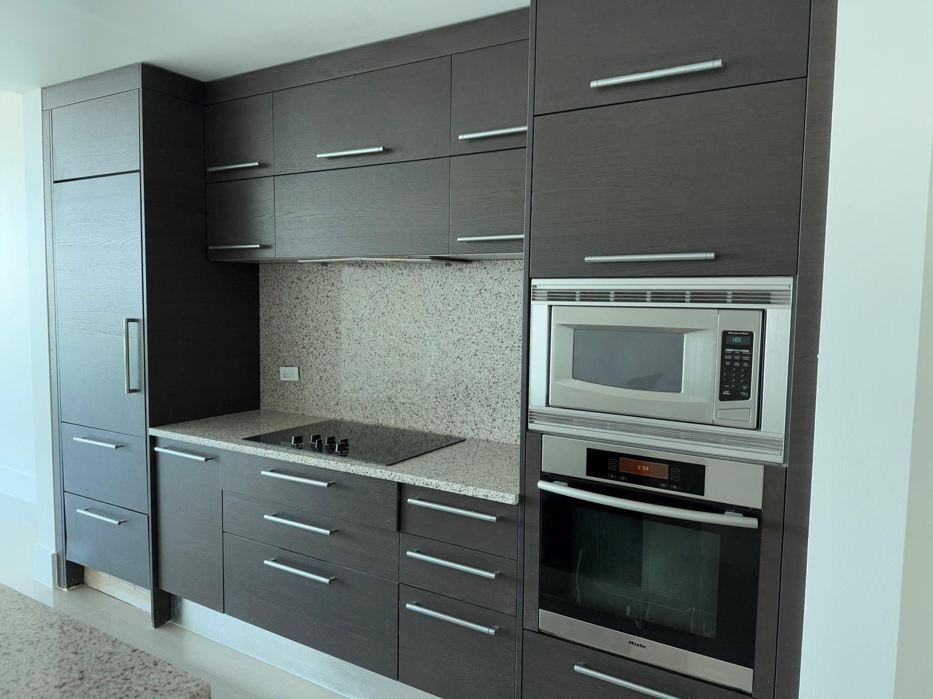 Modern kitchen cabinetry featuring dark wood-finish flat panel doors with brushed nickel hardware
