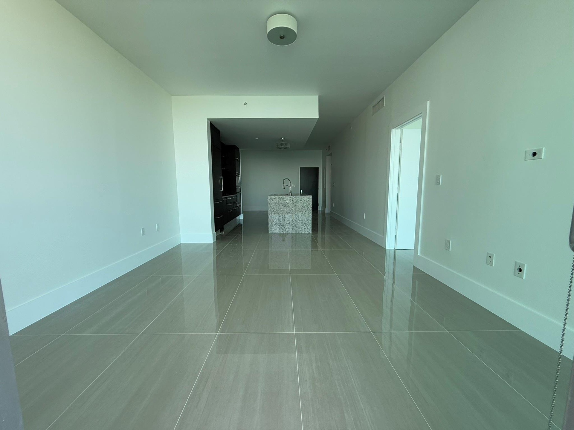Open-concept living space featuring large format tile flooring, high ceilings, recessed lighting, a modern kitchen island with an undermount sink, and
