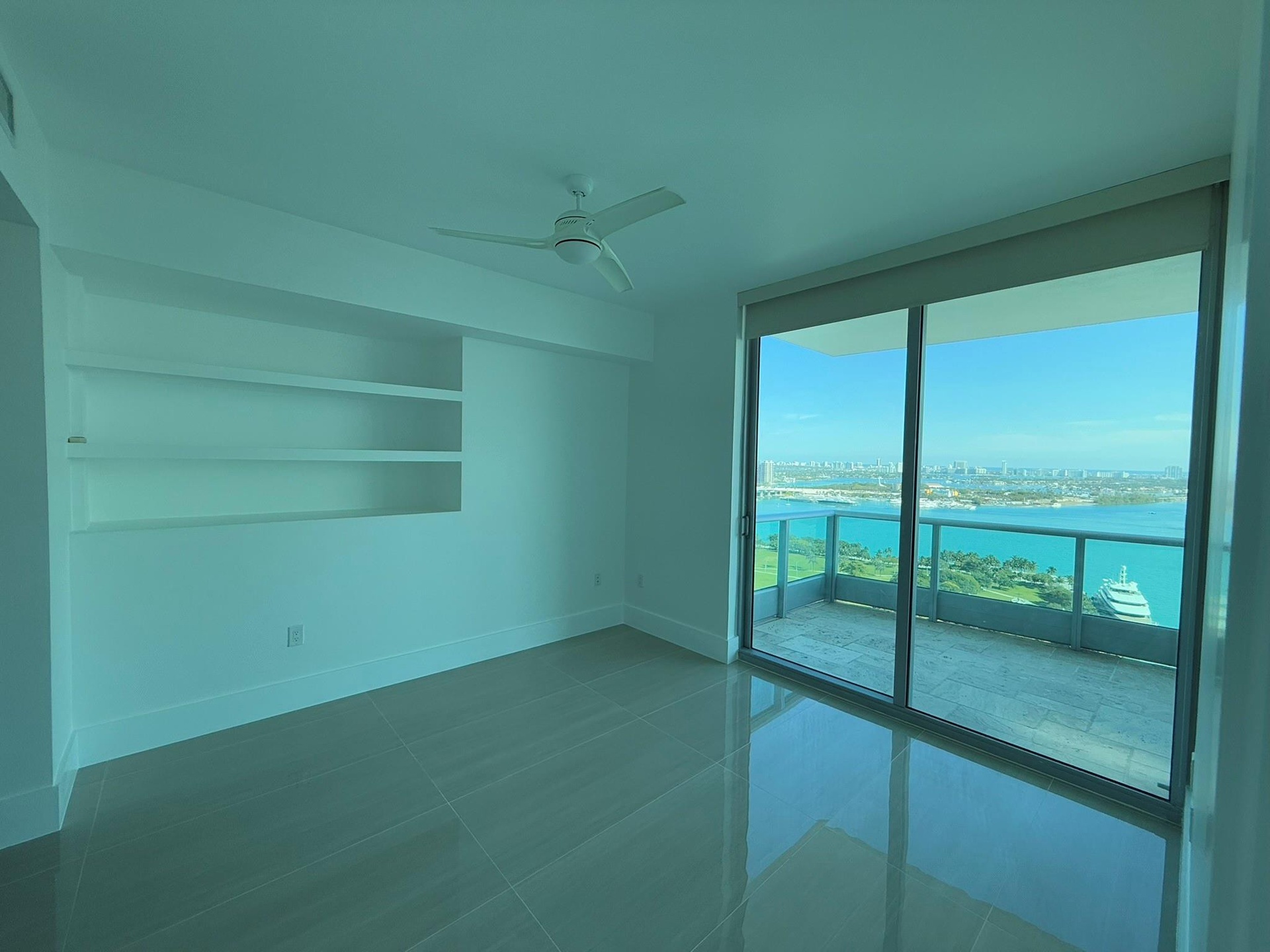 Expansive sliding glass doors opening to a balcony with water and city horizon