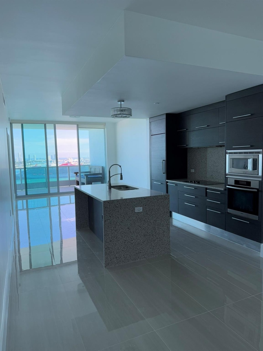 Contemporary kitchen featuring a speckled stone island with an undermount sink and gooseneck faucet