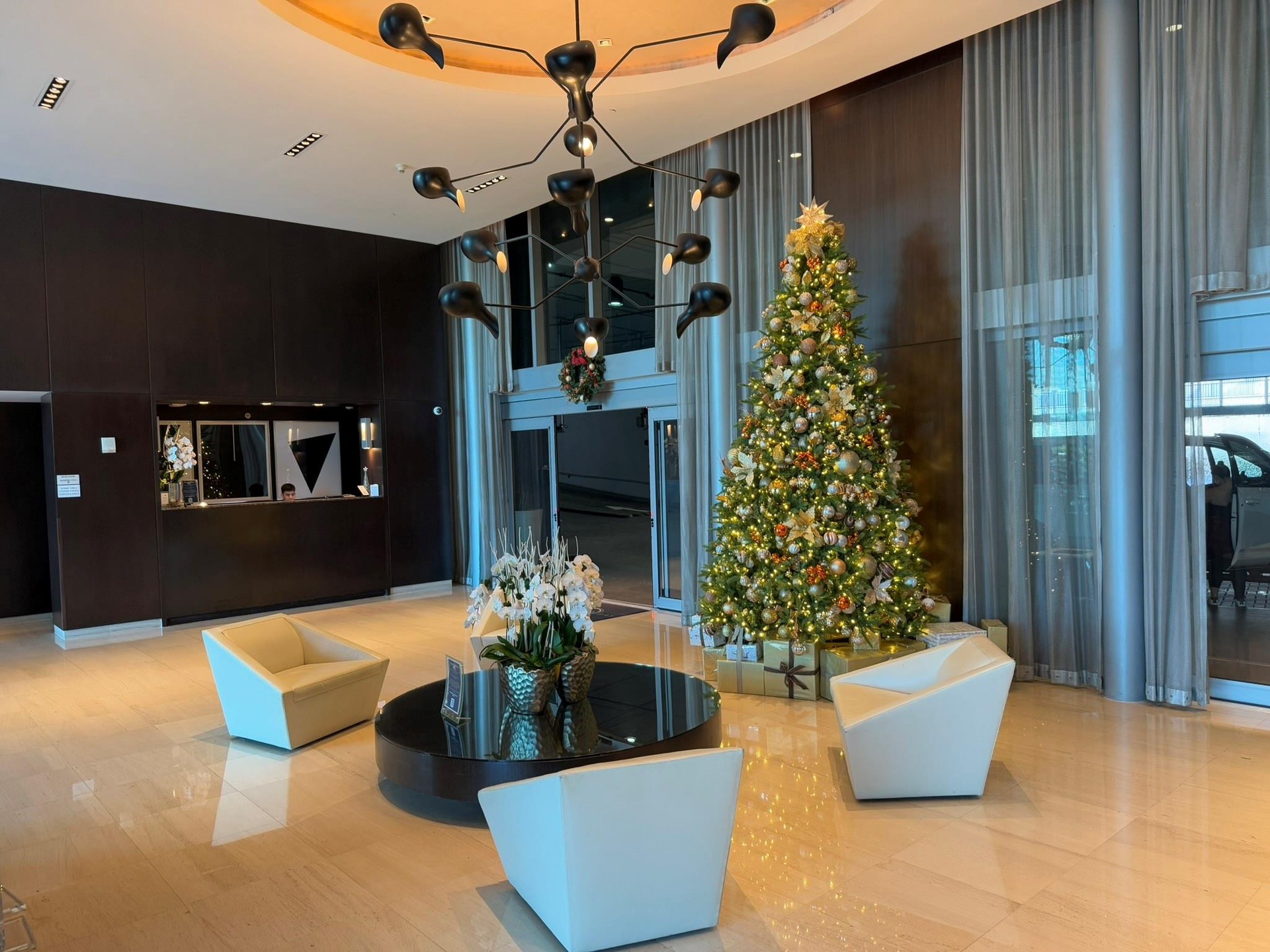 Spacious lobby featuring polished stone flooring, a contemporary chandelier, and a recessed ceiling design