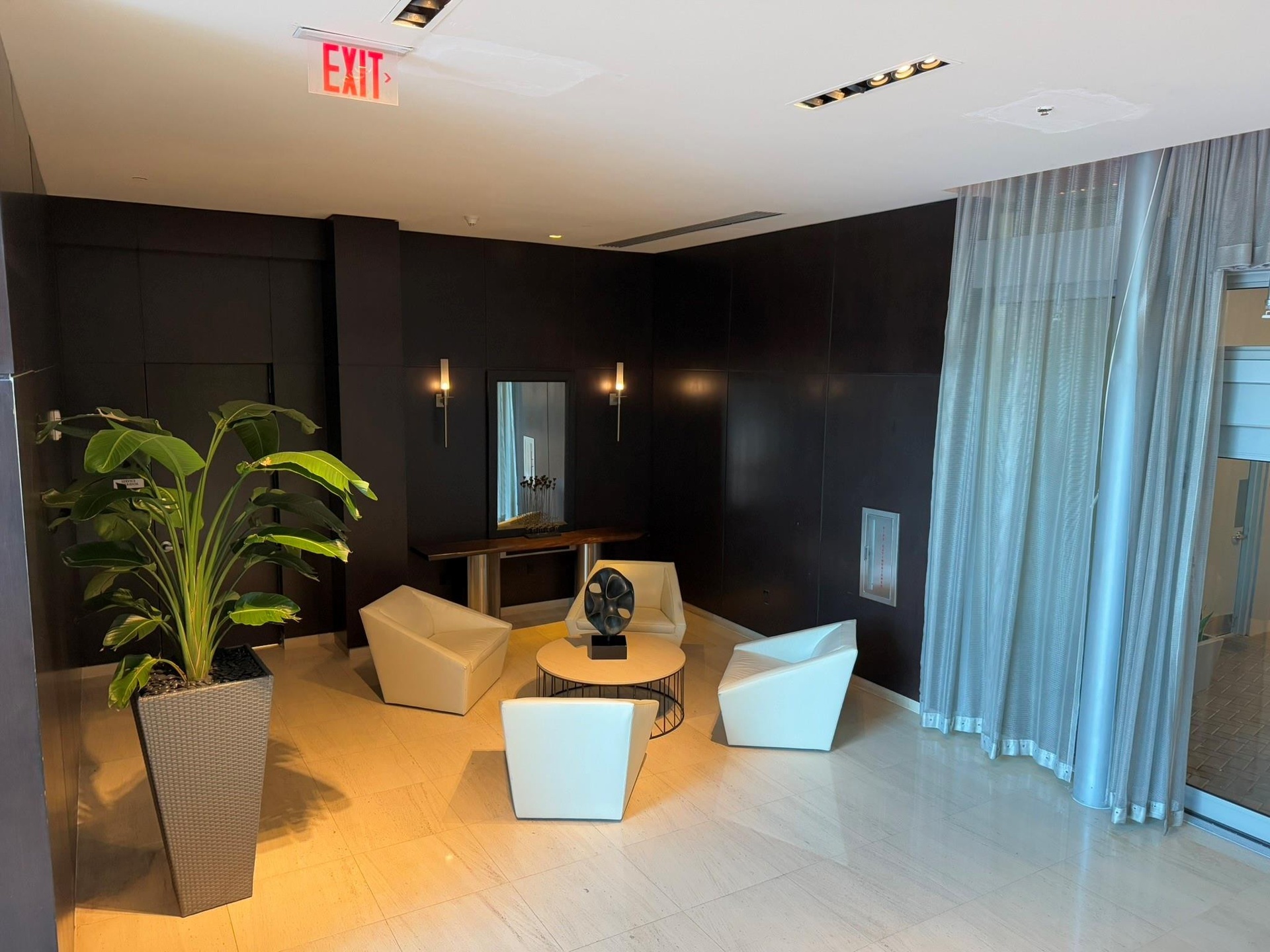 Elegant common area featuring dark paneled walls, polished tile flooring, and integrated ceiling lighting