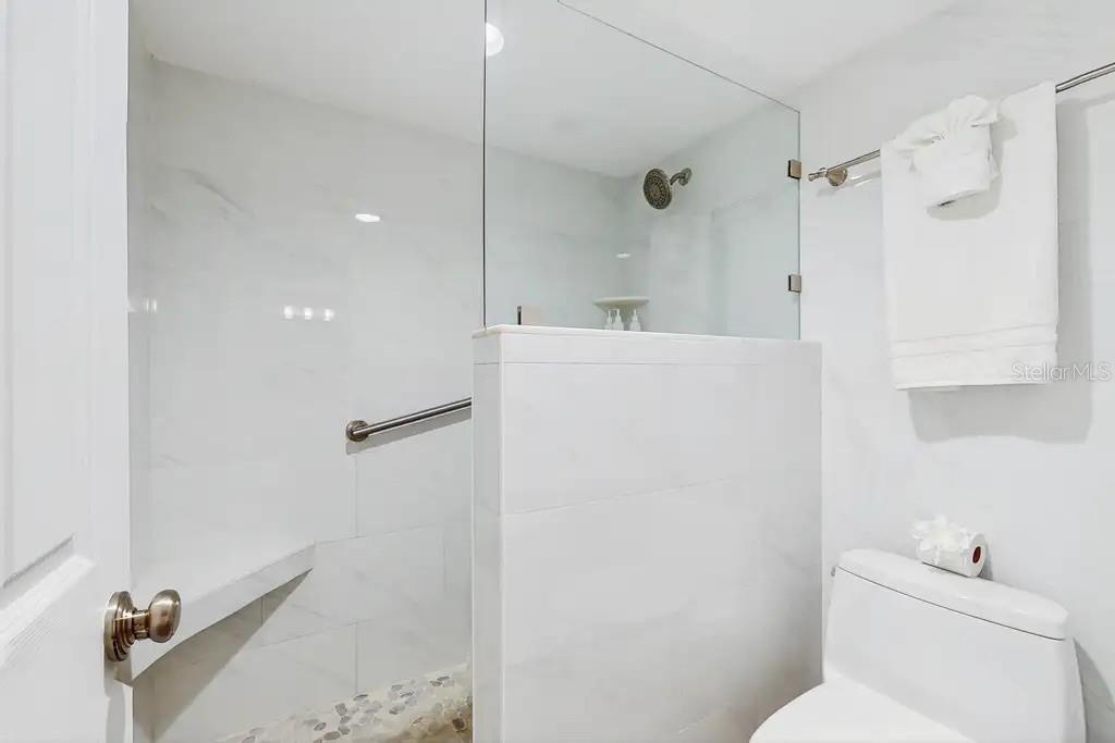 LARGE WALK-IN SHOWER OFF THE PRIMARY SUITE FEATURES A BUILT IN  BENCH FOR ADDED COMFORT AND RELAXATION.