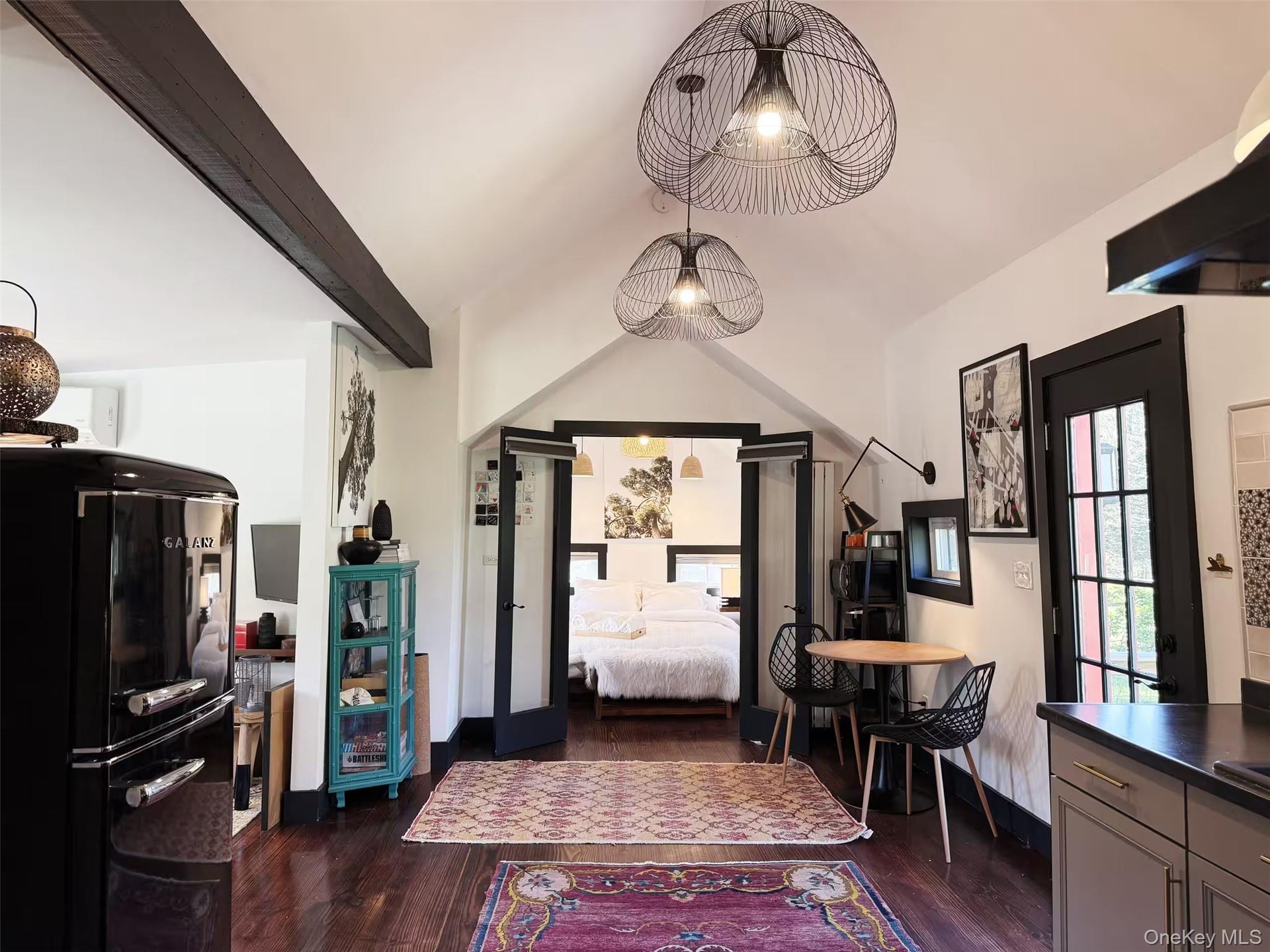 main living area vaulted and crate and barrel light fixtures with a clear view into the bedroom