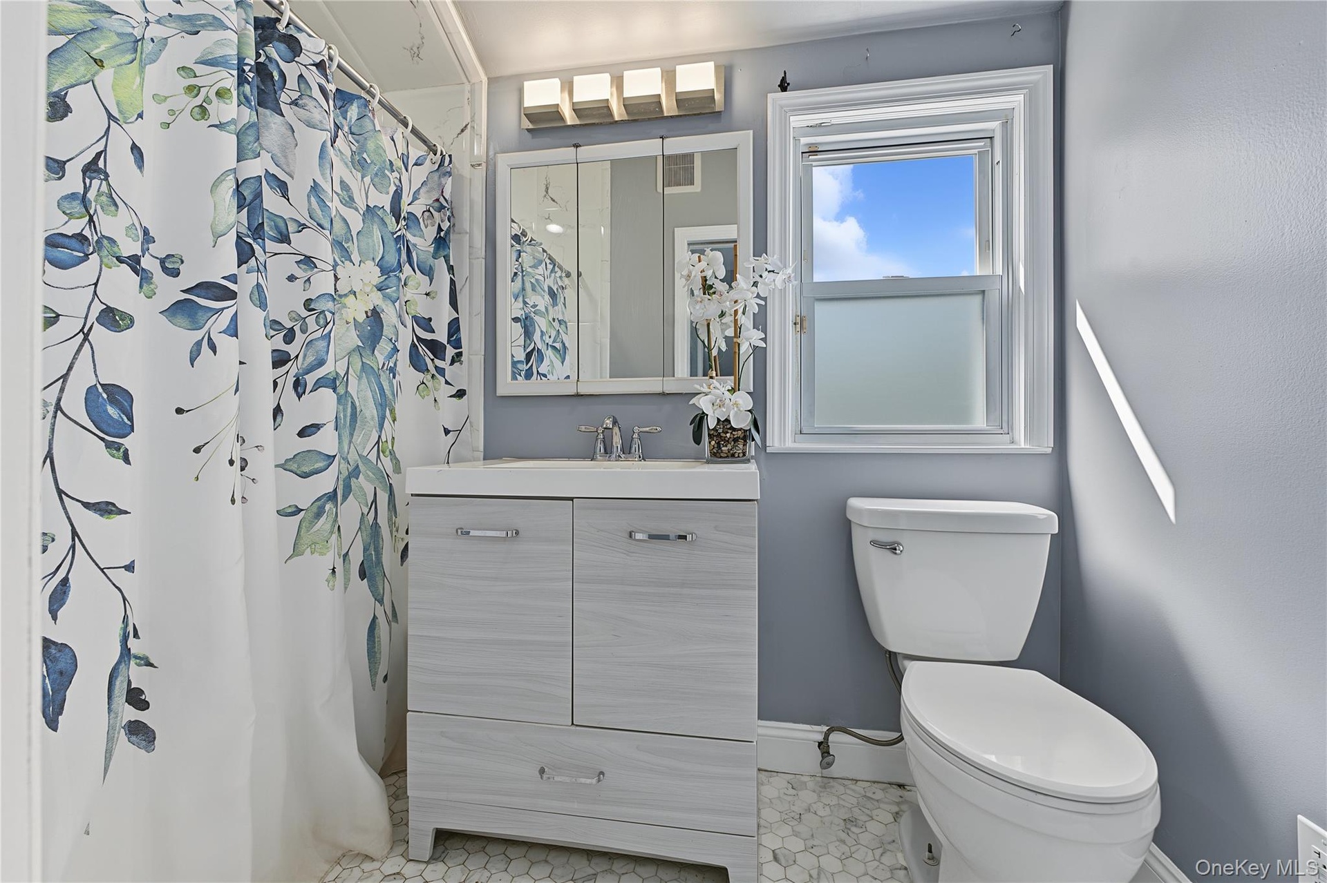 Second floor Bathroom featuring a single-sink vanity with cabinet storage, hexagon-patterned floor tiling, and a window