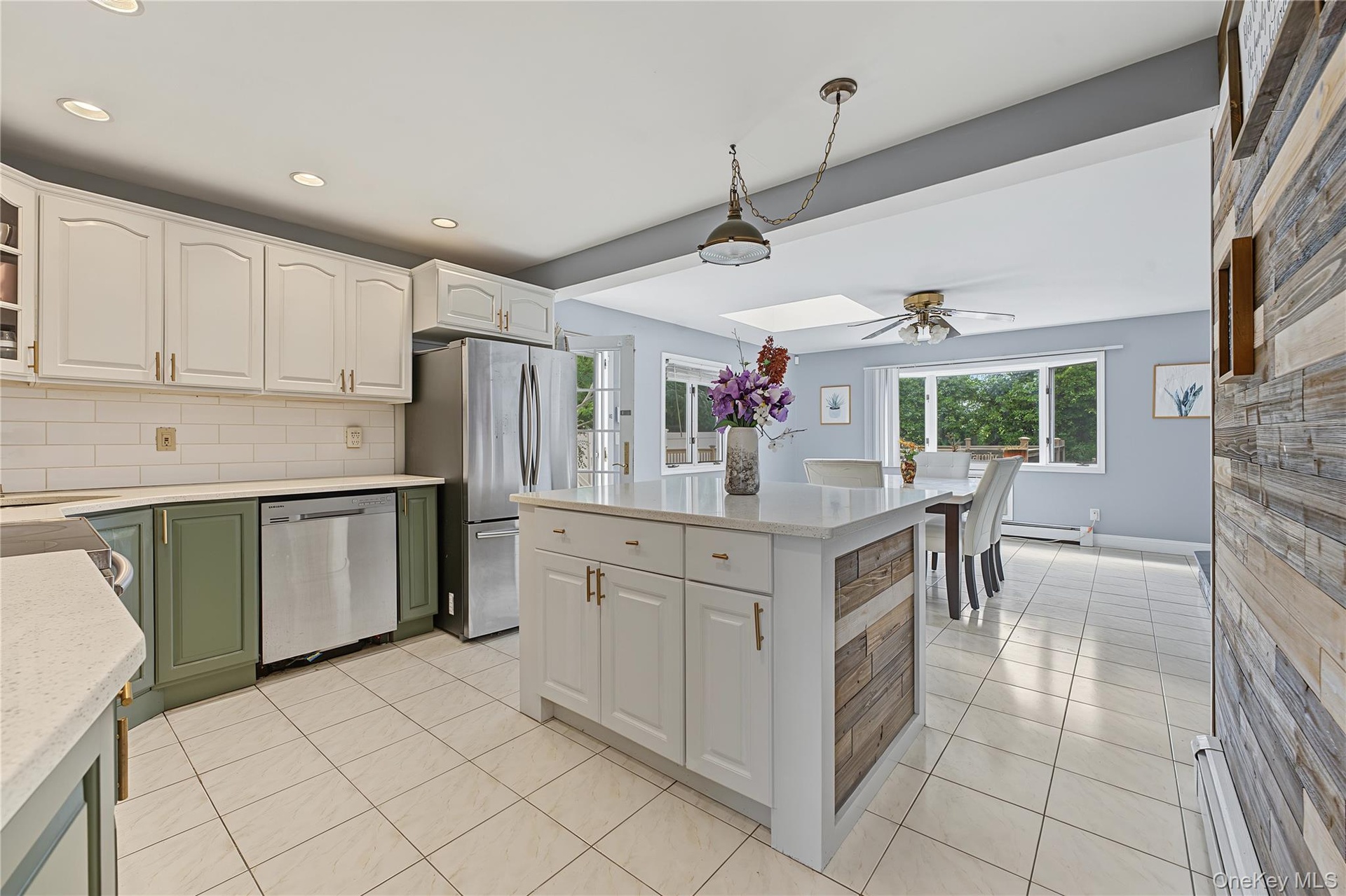 Open Kitchen featuring white shaker-style upper cabinetry, olive green lower cabinetry, stainless steel appliances, a center island that seats 2-3 wit