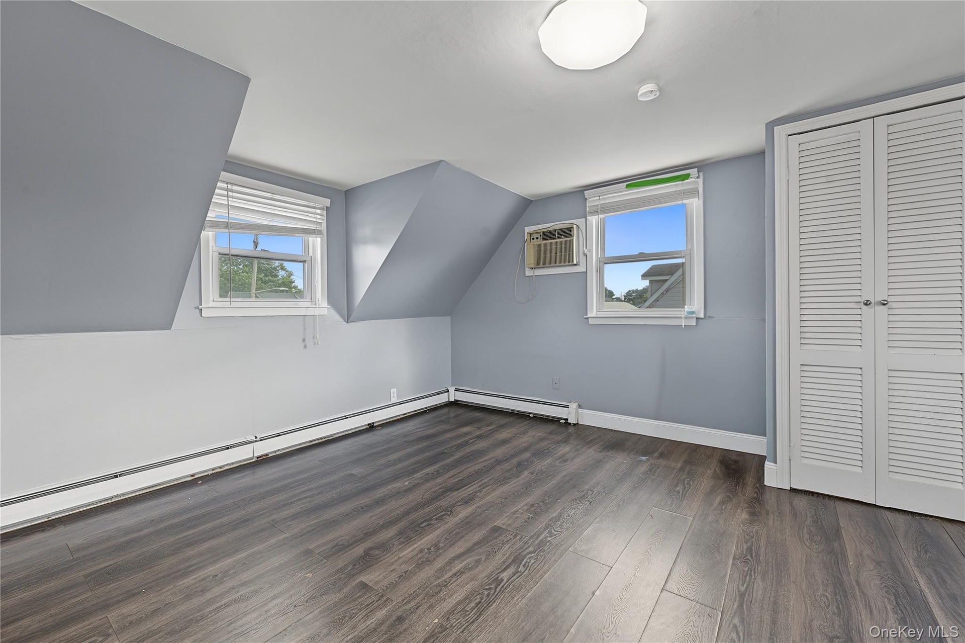 Fourth bedroom located on the second floor has two windows, bi-fold closet doors, and wall-mounted air conditioner