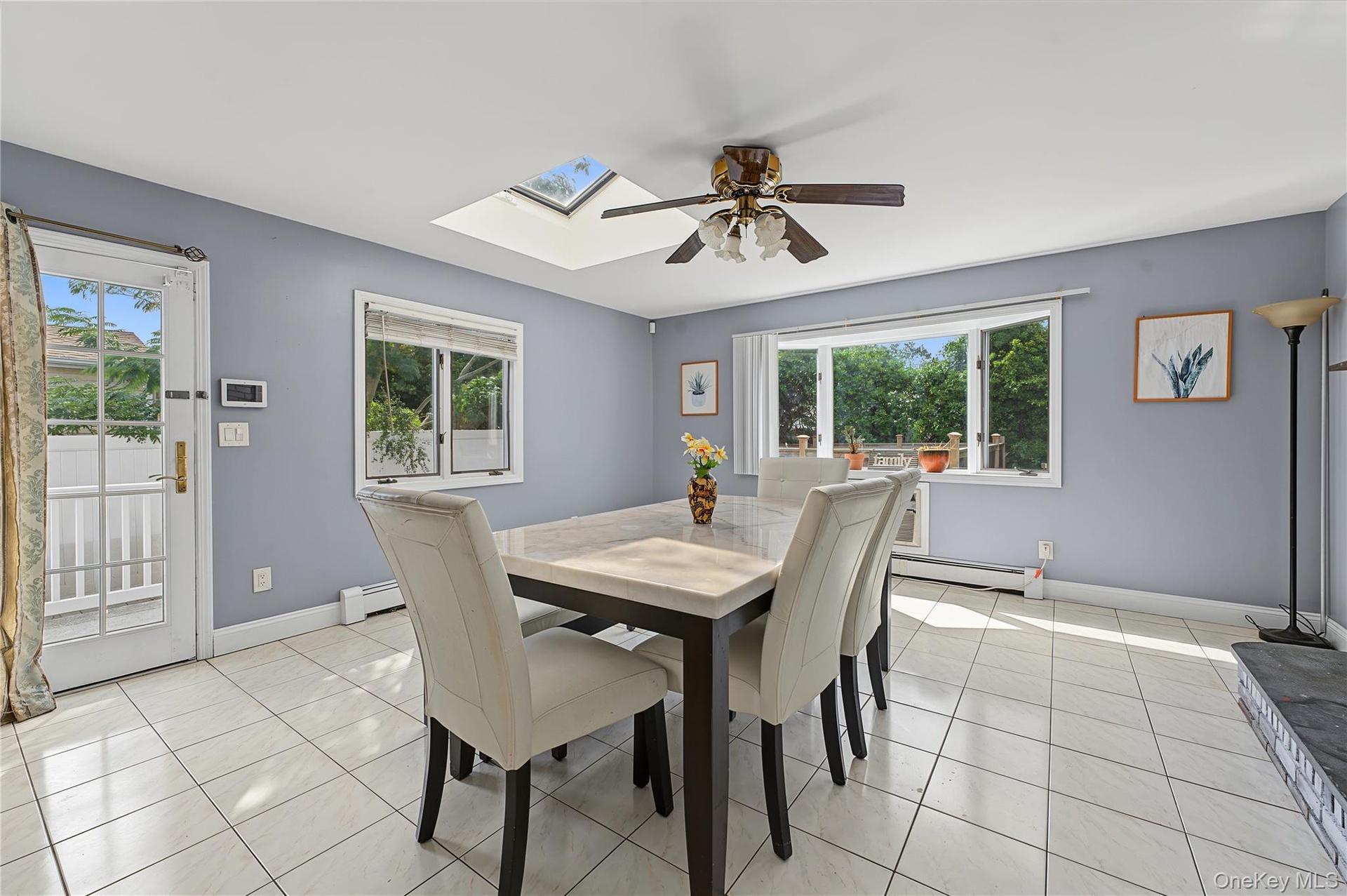 Skylight, ceiling fan,  door to the yard and garage access, tiled flooring, and multiple windows including a large bay window and wall mounted air con