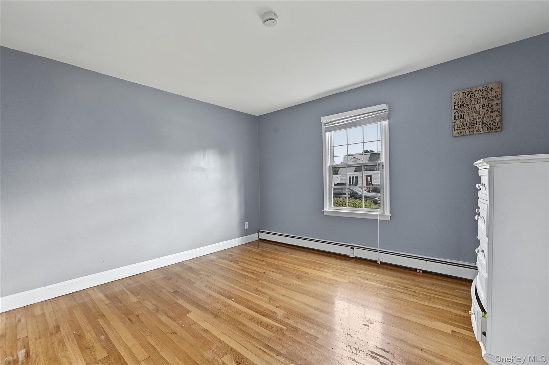 First floor bedroom Hardwood flooring, single window, baseboard heating, white trim and closet