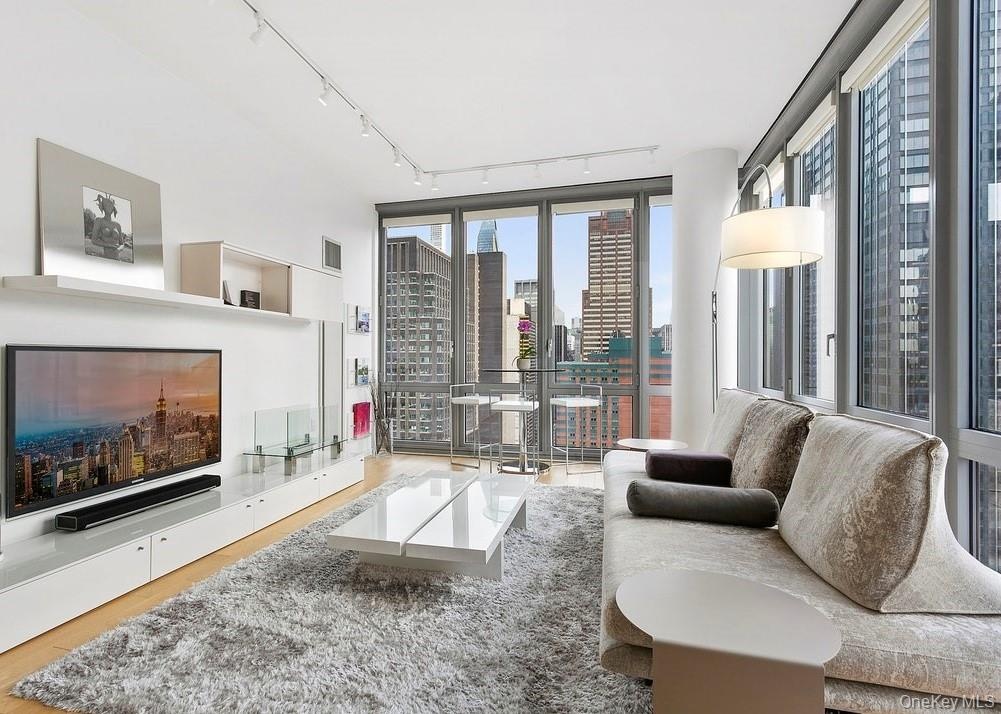 Living area featuring a city view, visible vents, floor to ceiling windows, and wood finished floors