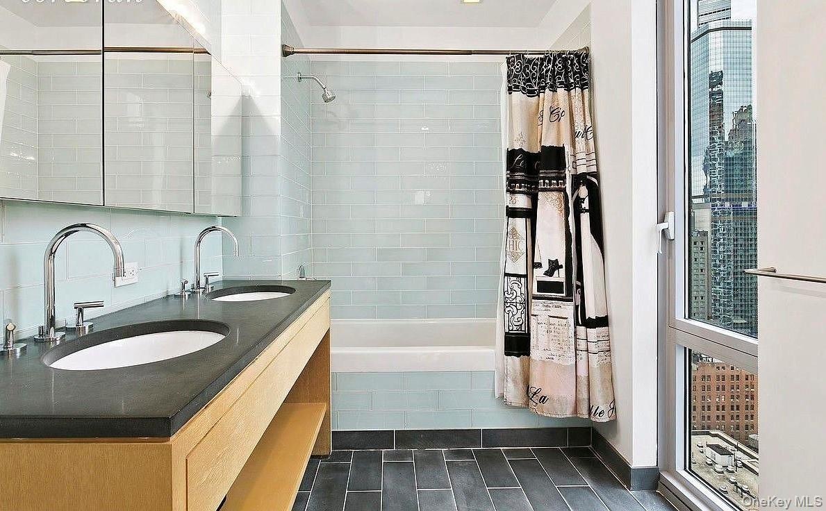 Bathroom with double vanity, tiled shower / bath combo, and a sink