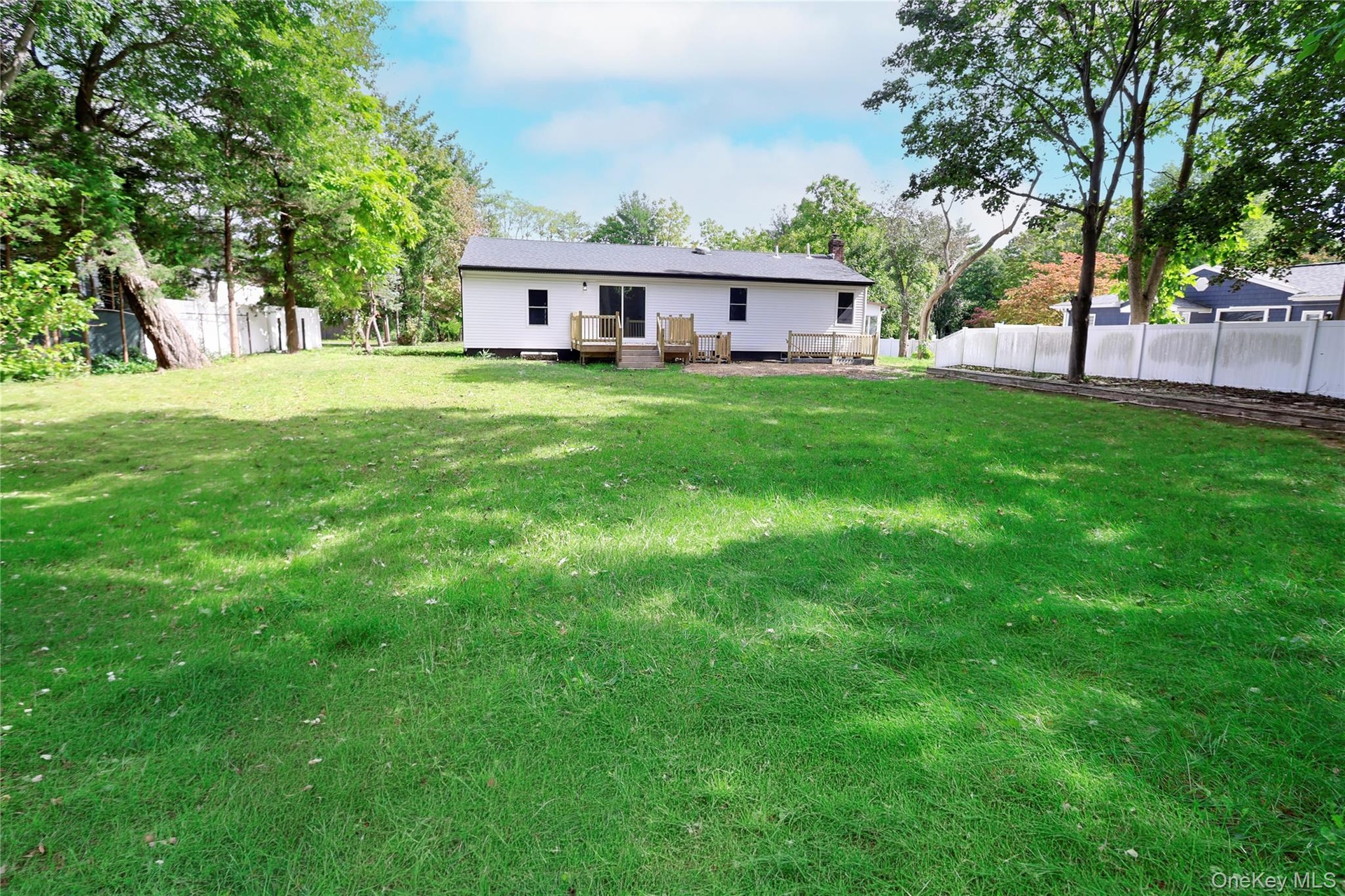 Expansive green lawn with mature trees and a privacy fence