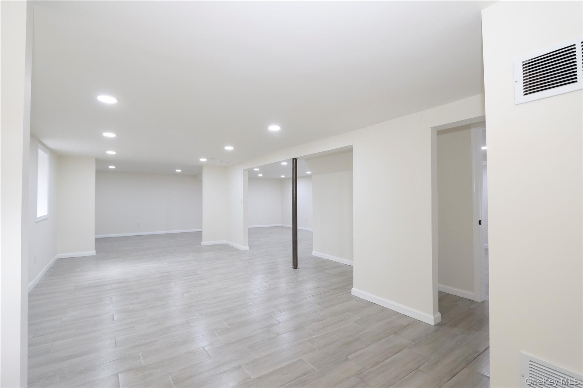 Open-concept lower level with recessed lighting, light-toned tile flooring, and white painted walls