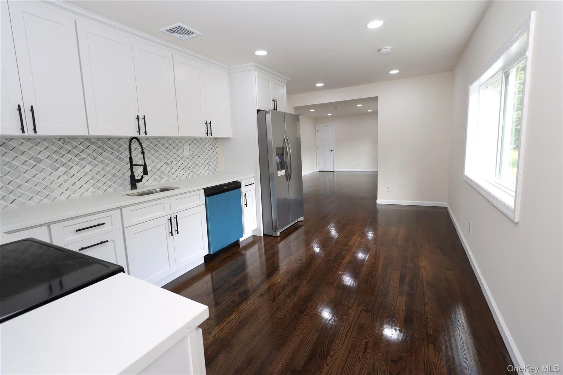 Kitchen featuring white shaker cabinetry, white countertops, a mosaic tile backsplash, dark wood-finish flooring, and recessed lighting