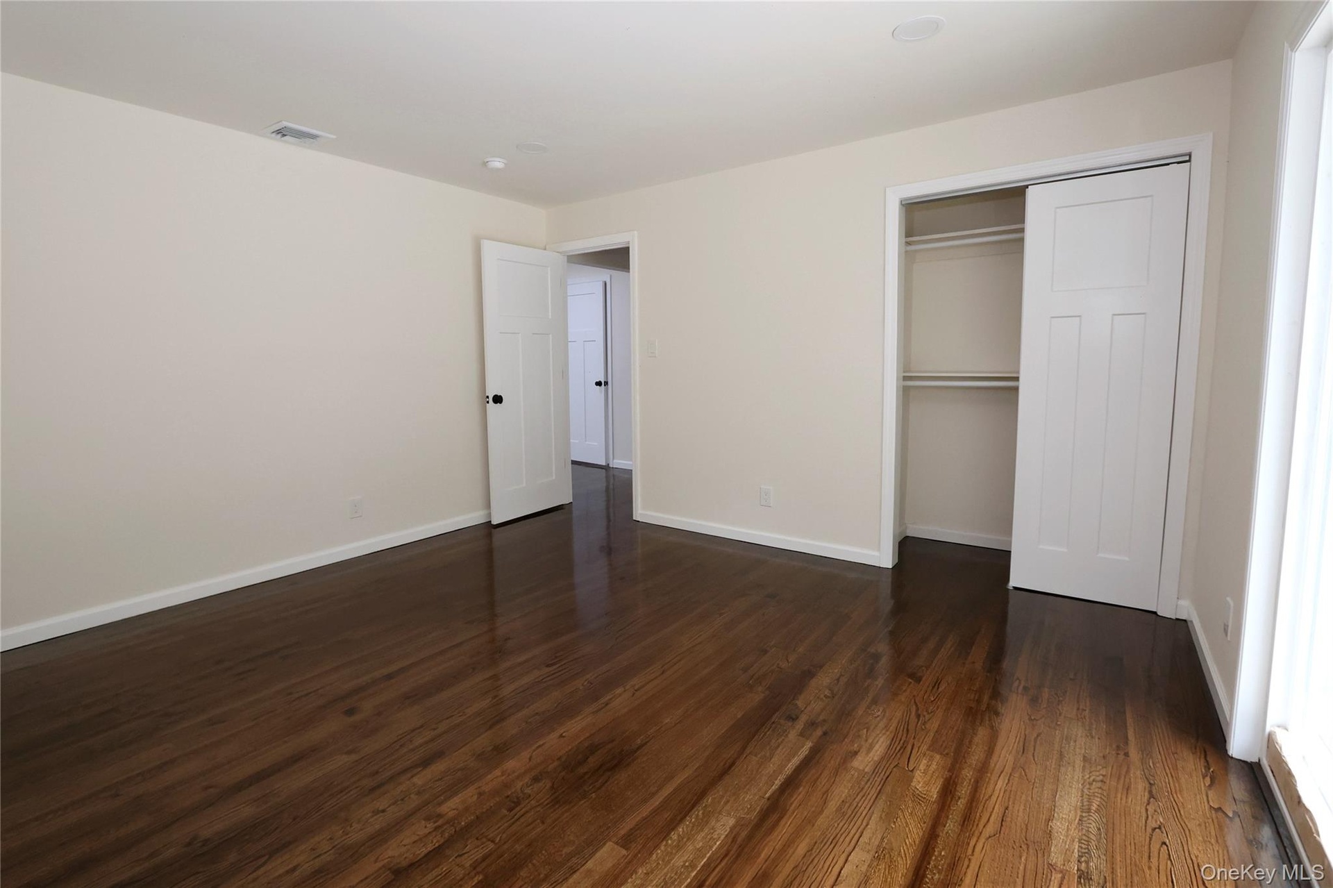 Hardwood flooring, painted walls, white trim, sliding closet doors, and recessed lighting