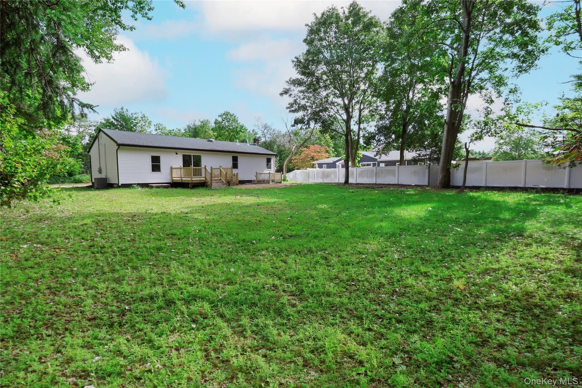 Expansive green lawn with a white privacy fence
