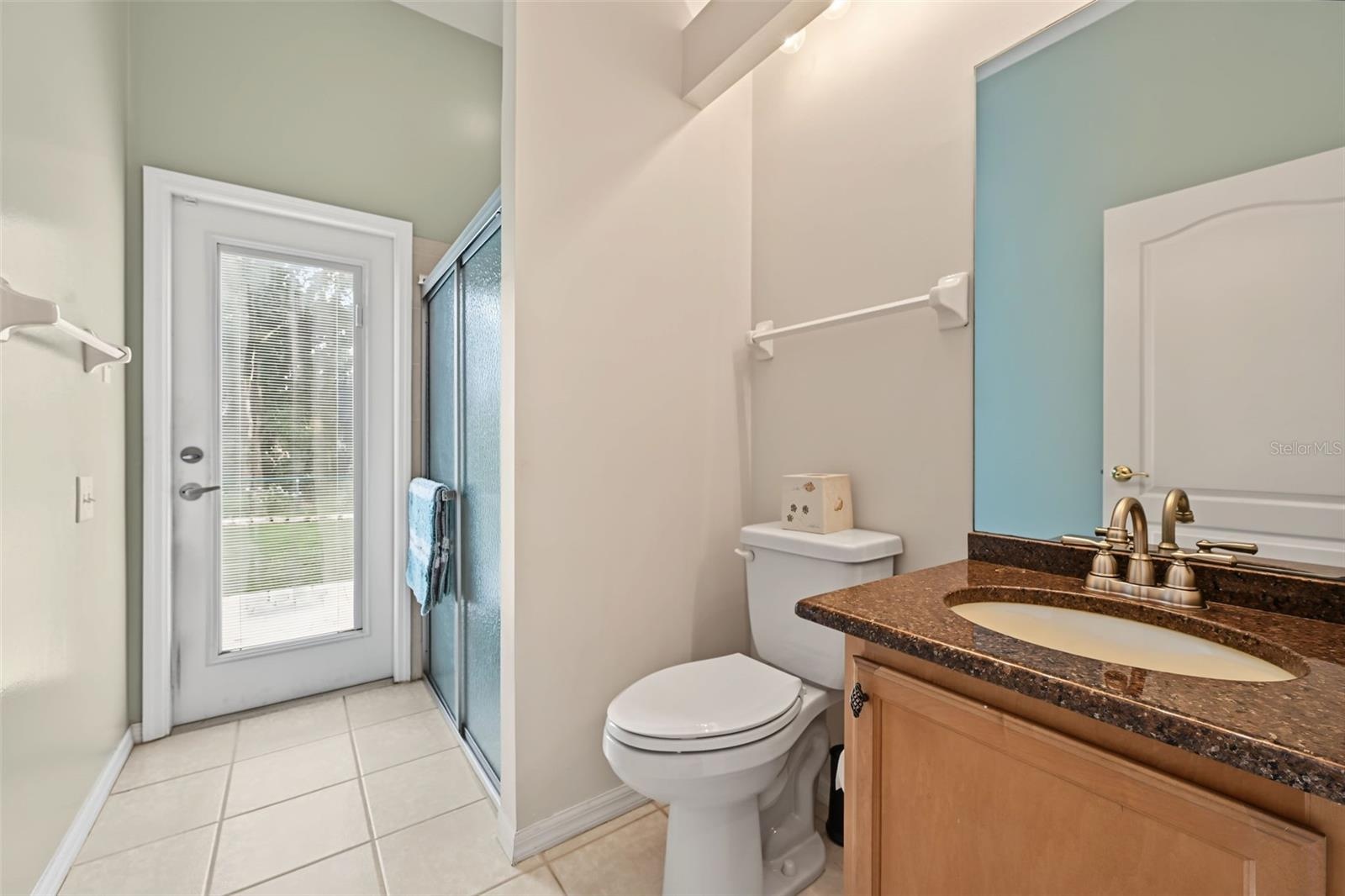 Third bathroom at rear of home next to fourth bedroom.  Door leading to back yard and pool area.