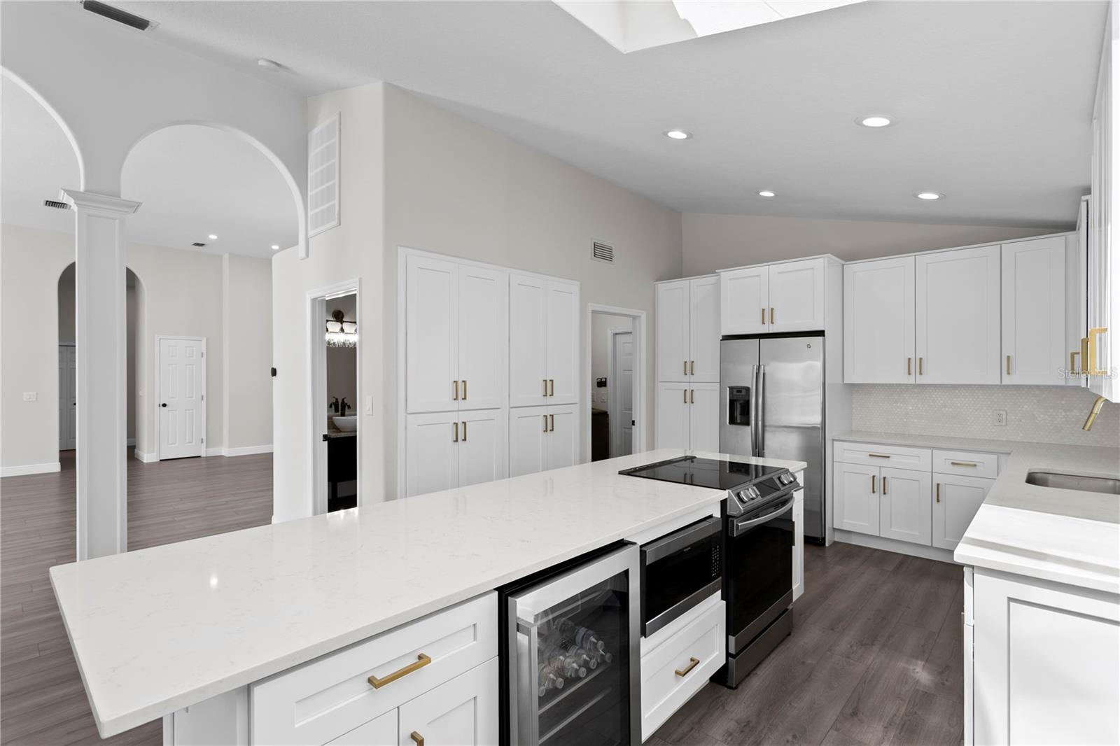 Well-appointed kitchen island featuring a wine refrigerator, microwave, range, additional cabinet storage and breakfast bar seating.