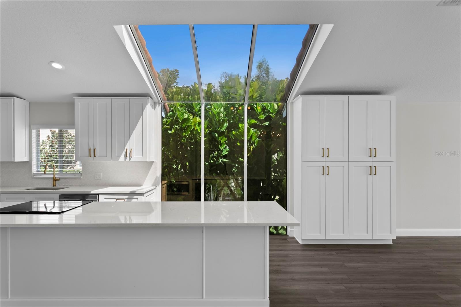 Floor-to-ceiling windows fill the gorgeous kitchen with natural light, complemented by abundant cabinet storage.