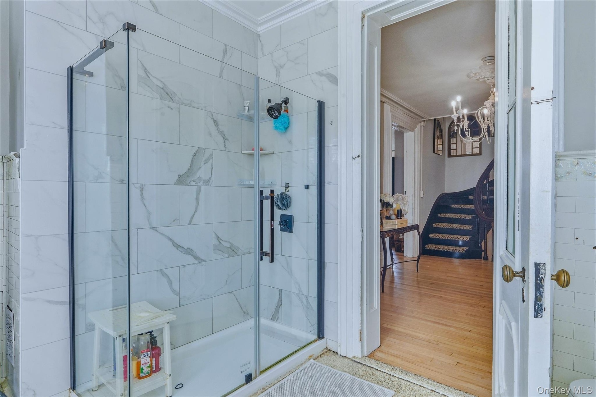 Glass-enclosed shower with subway tile surround, matte black shower fixtures, and integrated shelving