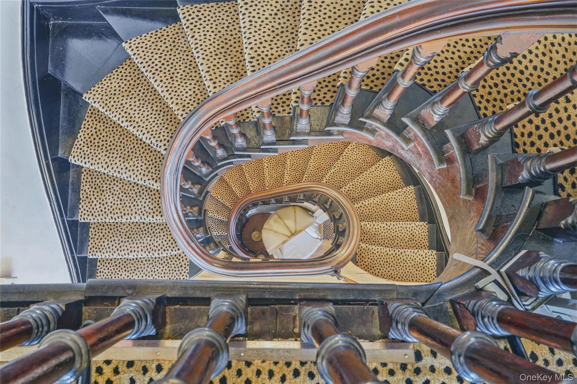 Curved staircase featuring dark wood railing and balusters, with patterned stair runner