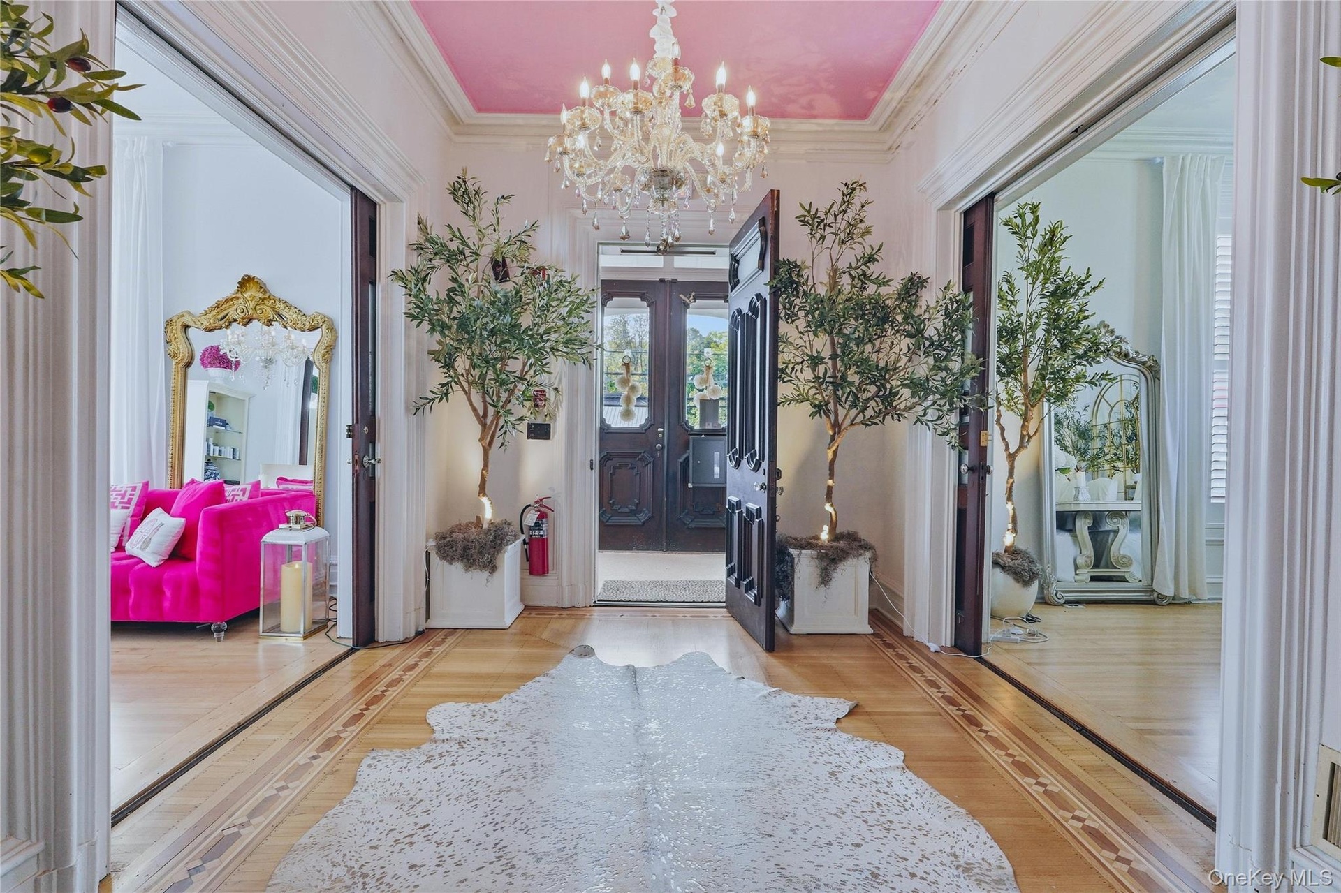 Grand entryway featuring a decorative chandelier, dual paneled doors, and light wood-finish flooring with intricate inlay