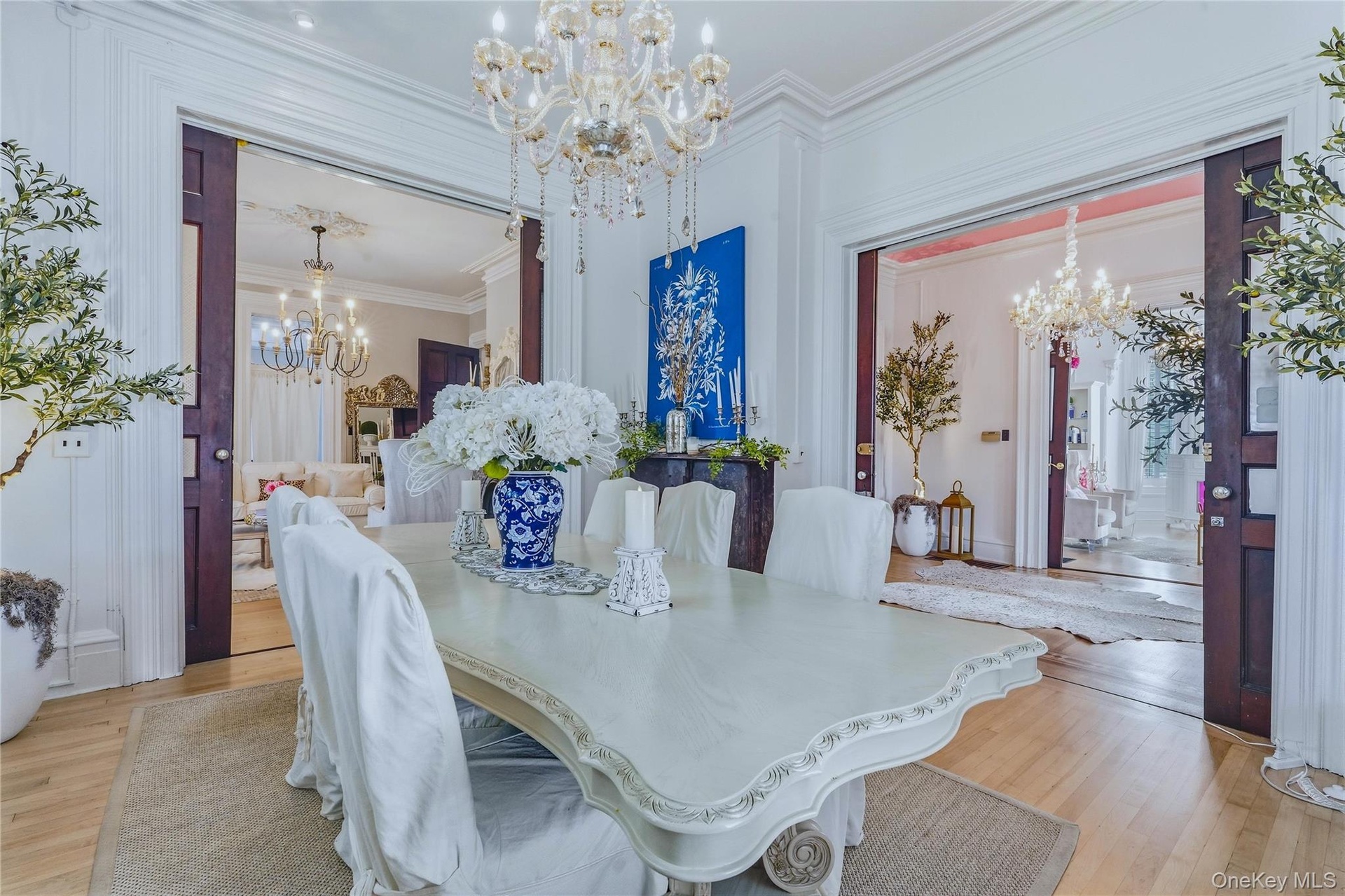 Ornate chandelier, decorative crown molding, light wood-finish flooring, and pocket doors