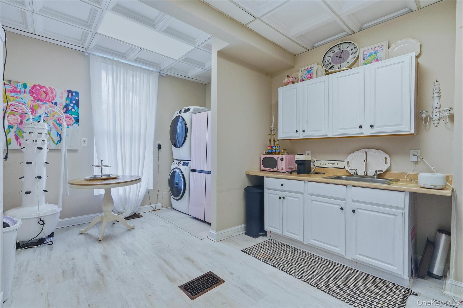 White wood-finish flooring, white cabinetry, integrated sink, and patterned ceiling panels