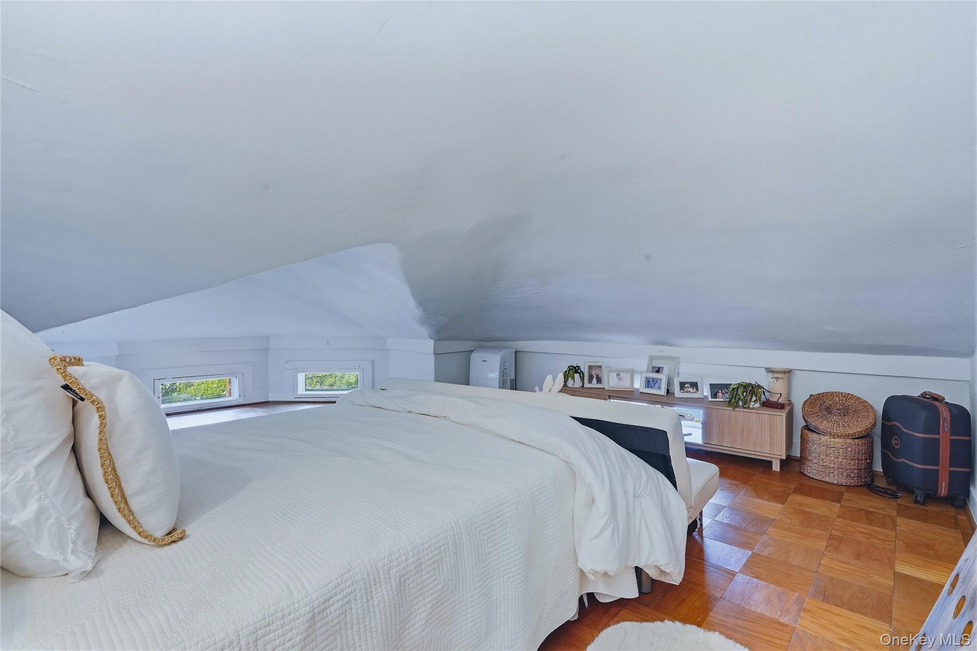 Sloped ceiling design with multiple windows and wood-finish flooring