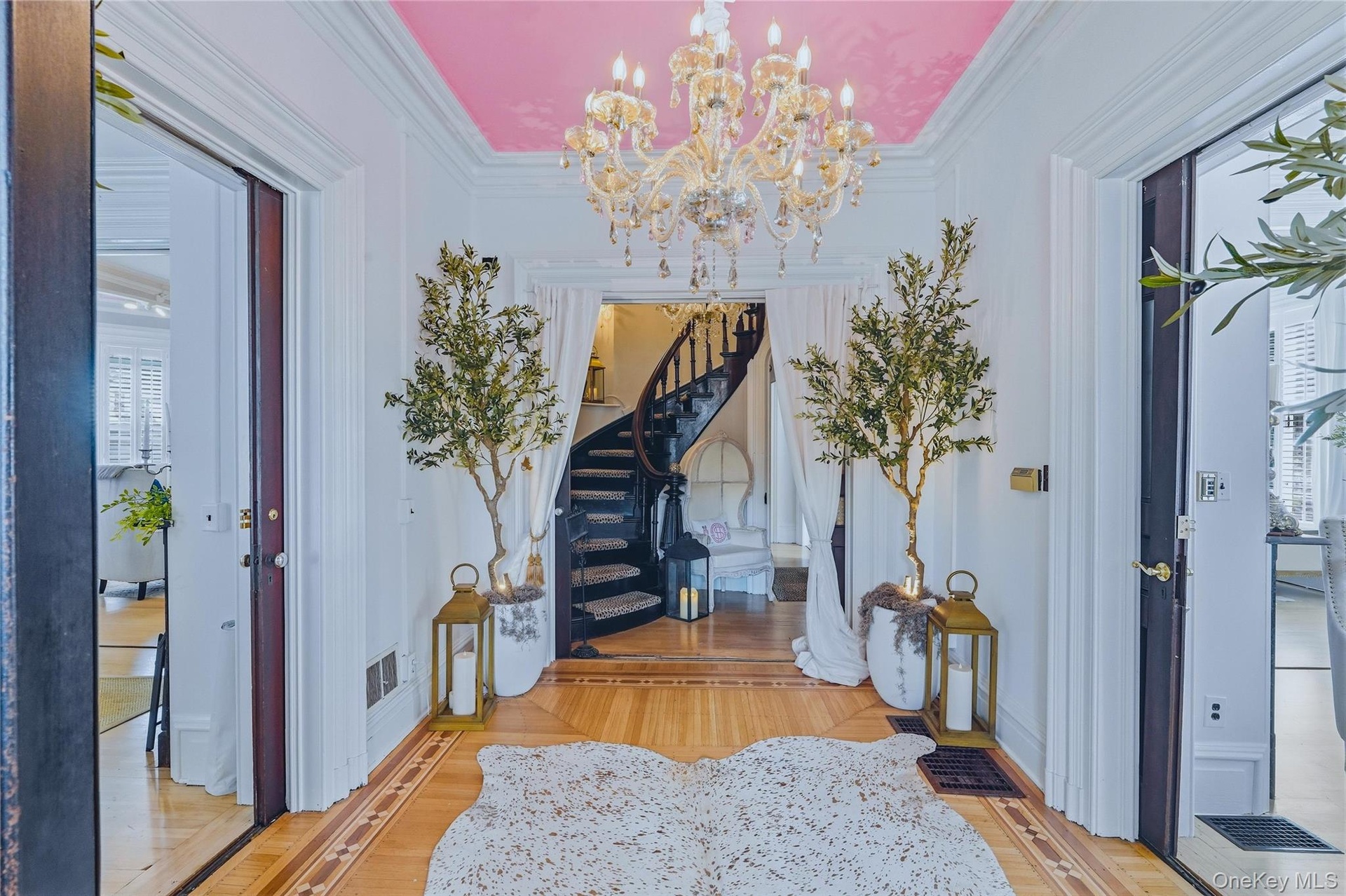 Foyer featuring a large chandelier, wood-finish flooring with inlay details, and a visible spiral staircase