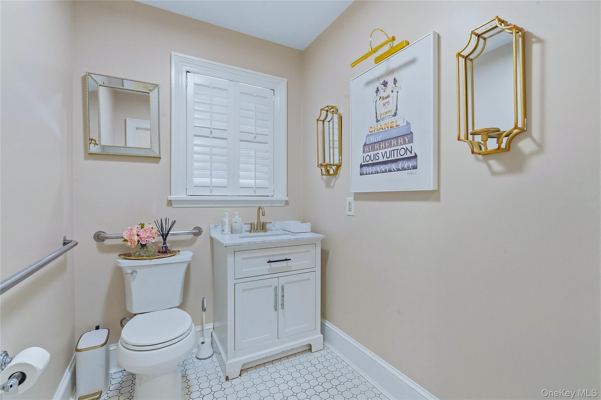 White shaker-style vanity with a solid surface countertop and gold-tone faucet