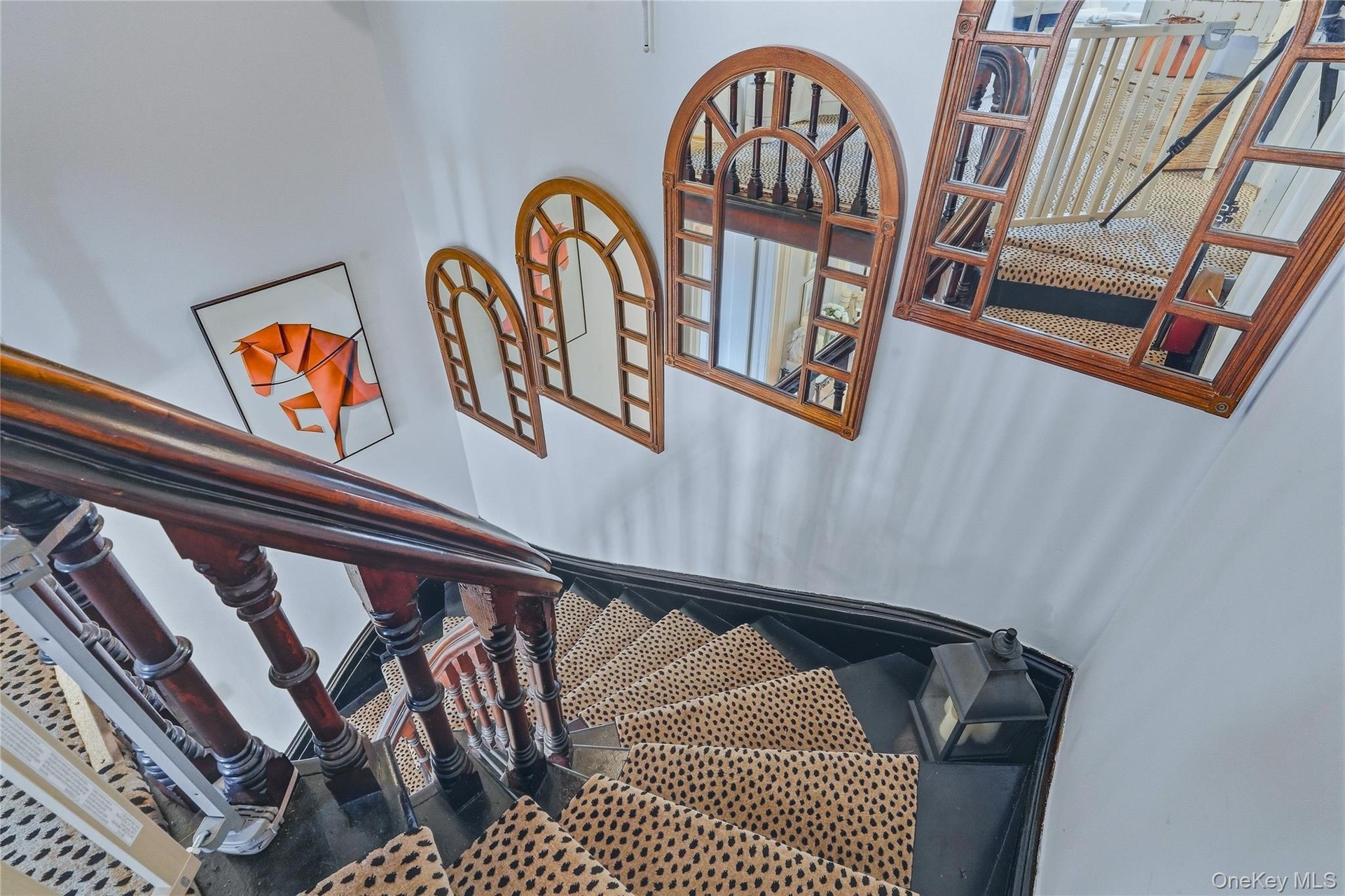 Staircase featuring dark wood banister and balusters, painted risers, and decorative wall mirrors