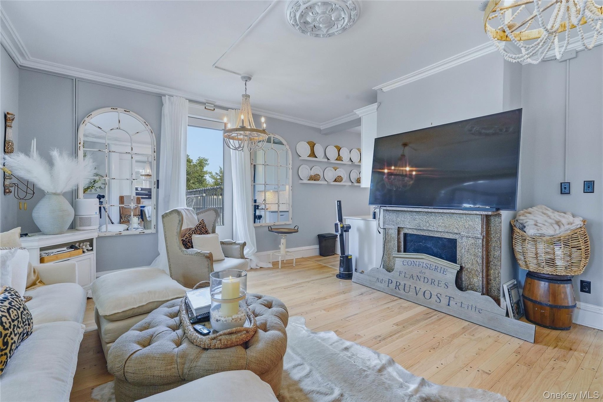Light wood-finish flooring, decorative ceiling medallion, sliding glass door, stone fireplace surround, and crown molding