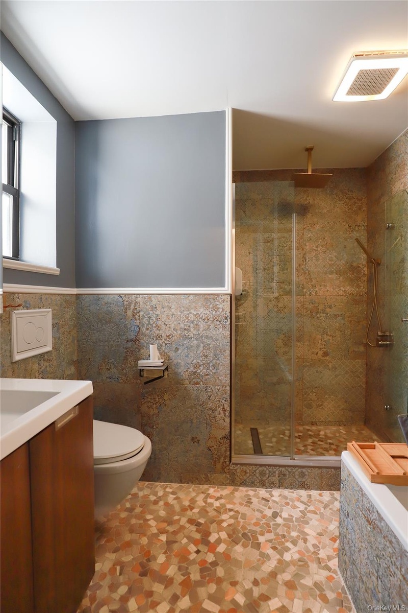 Mosaic tile flooring with a walk-in shower featuring a glass enclosure