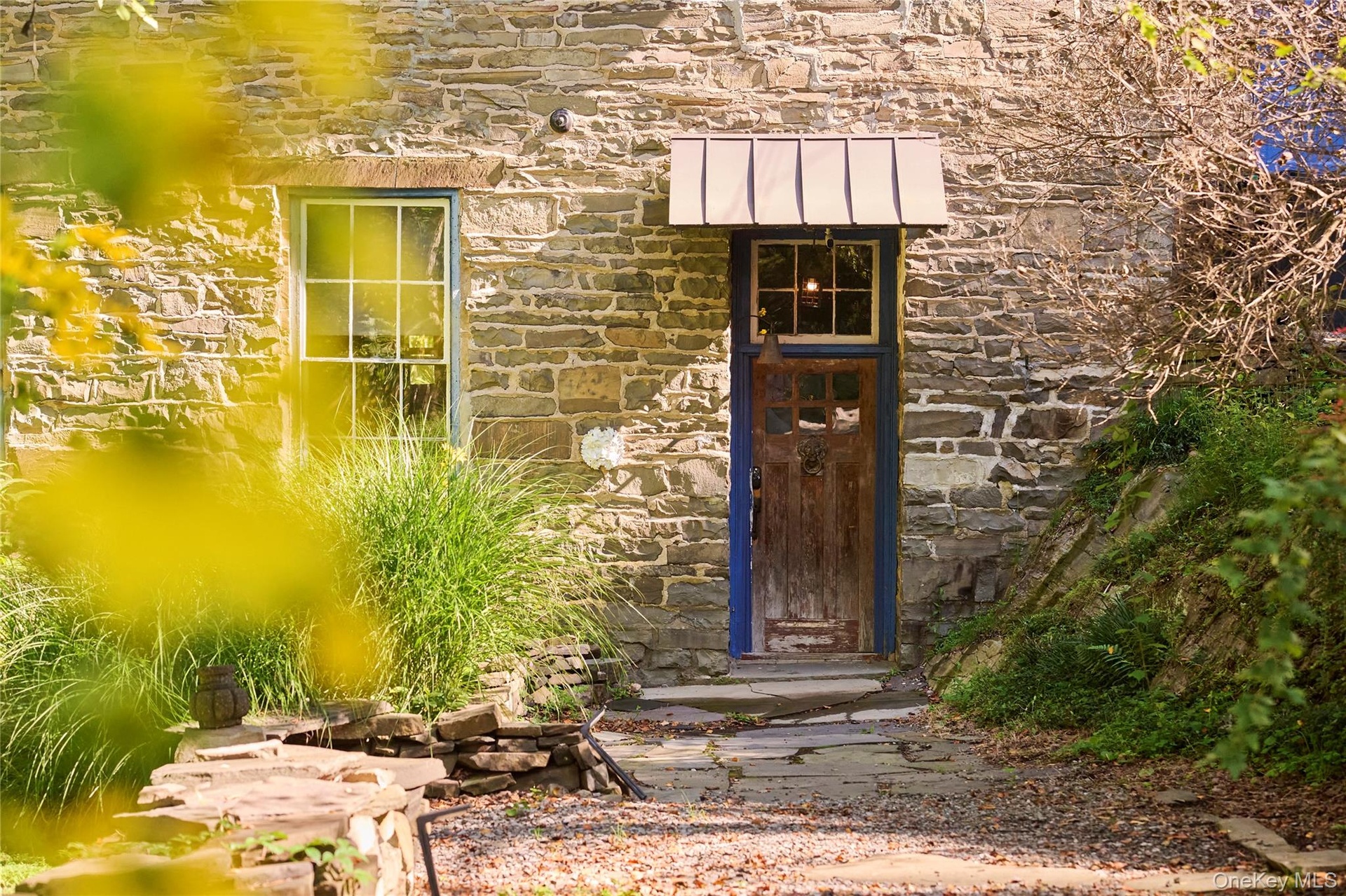 Doorway to property with stone siding, a standing seam roof, and a metal roof