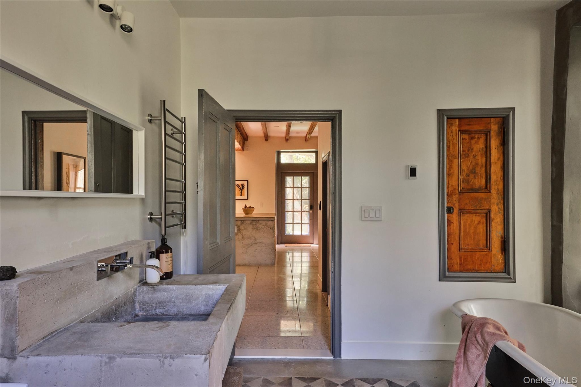 Bathroom featuring a freestanding tub, vanity, a towel warmer, and beam ceiling
