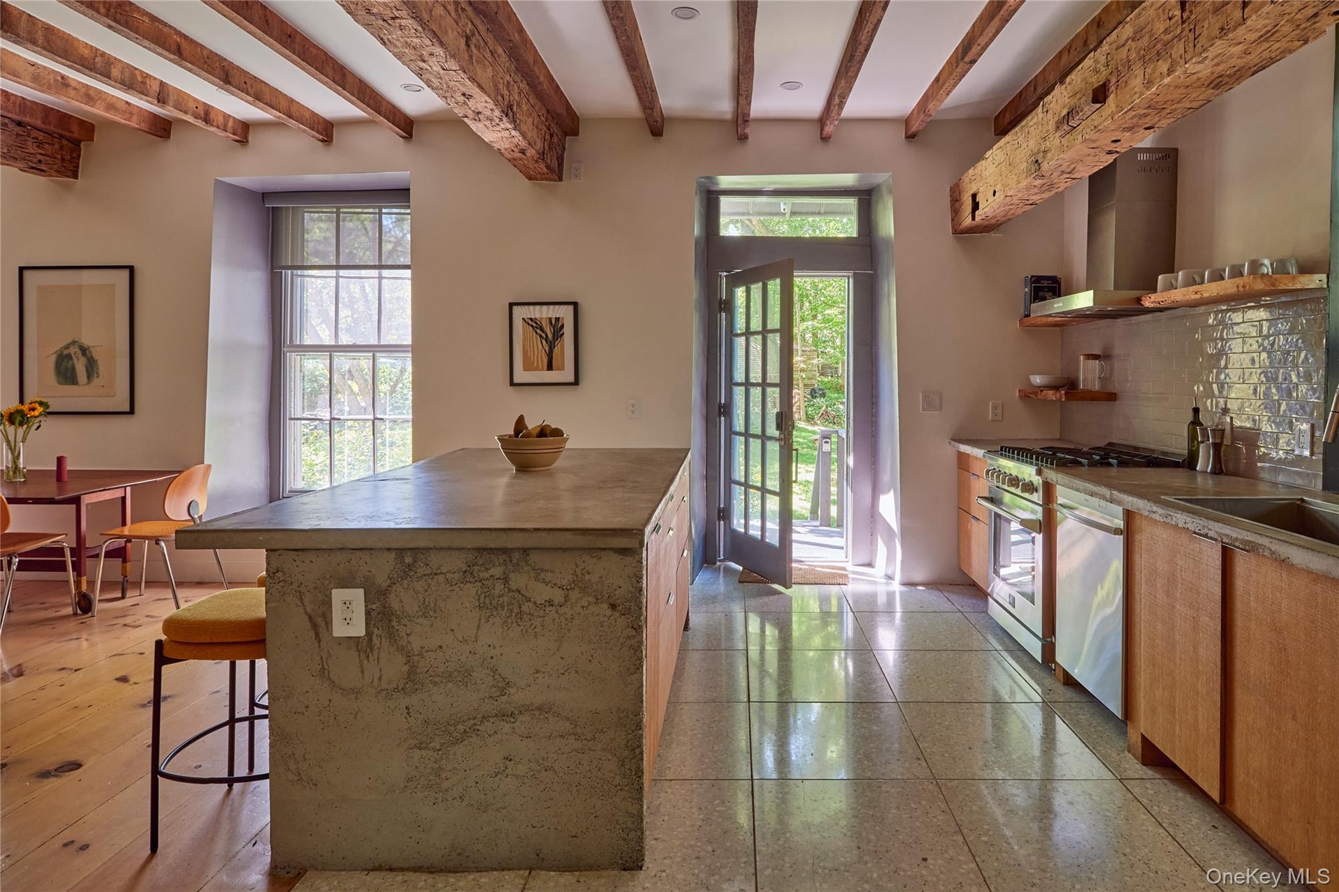 Kitchen with open shelves, wall chimney exhaust hood, backsplash, a breakfast bar area, and beam ceiling